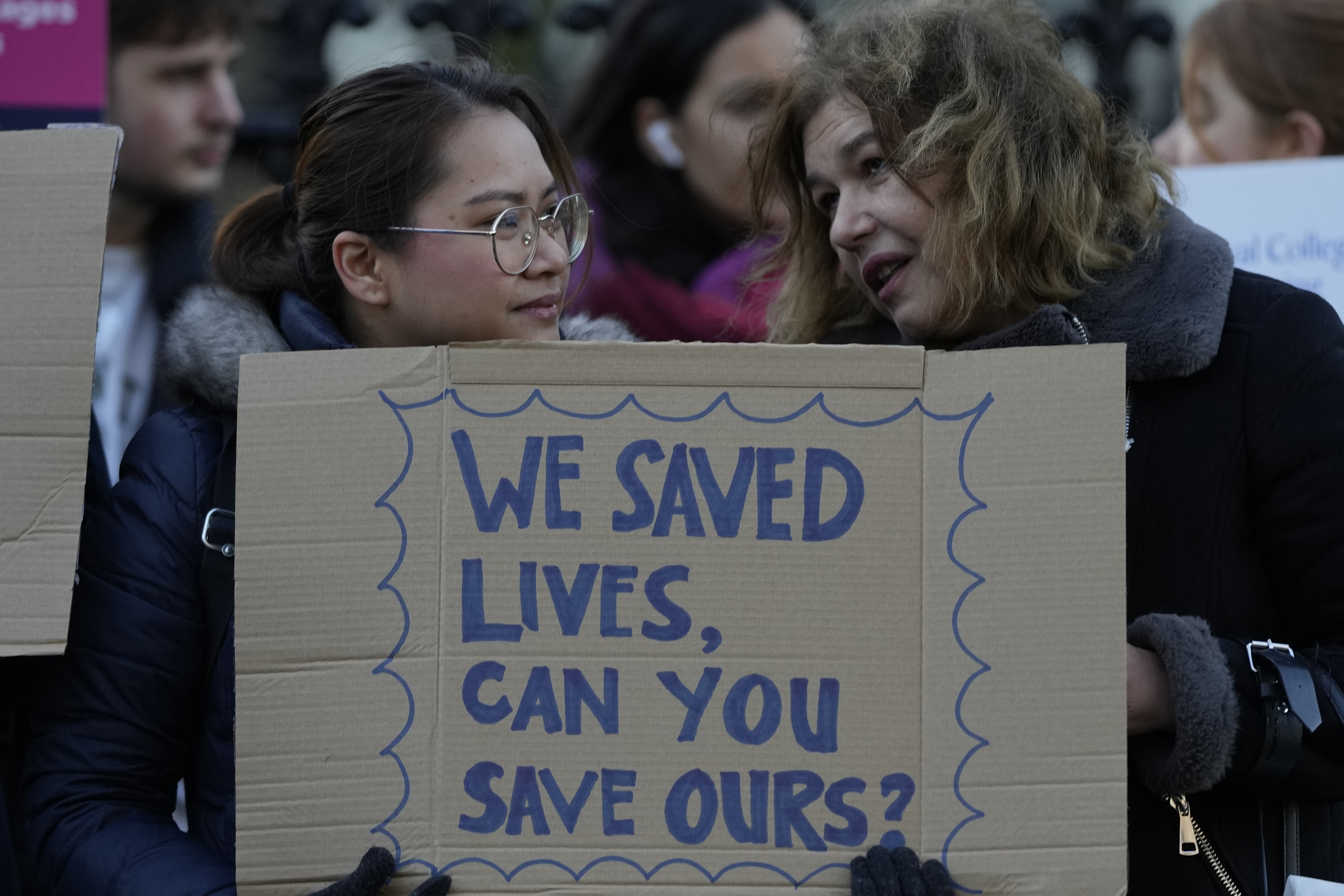 Two demonstrators hold a placard in support of the strike by nurses outside St Thomas Hospital in London
