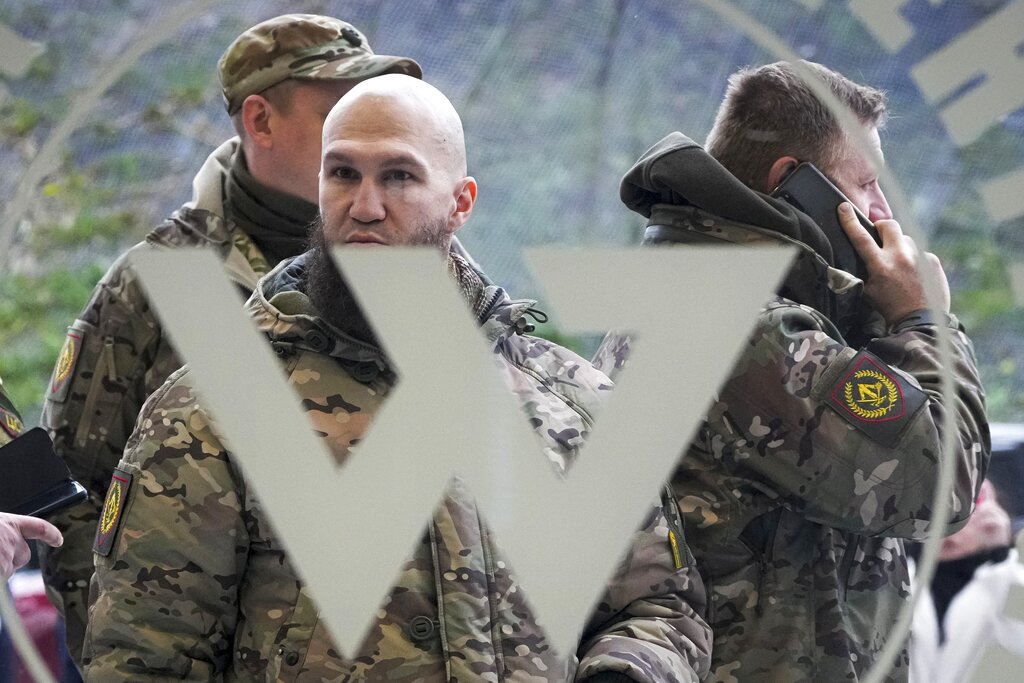 Visitors wearing military camouflage stand at the entrance of the 'PMC Wagner Centre', which is associated with businessman and founder of the Wagner private military group Yevgeny Prigozhin
