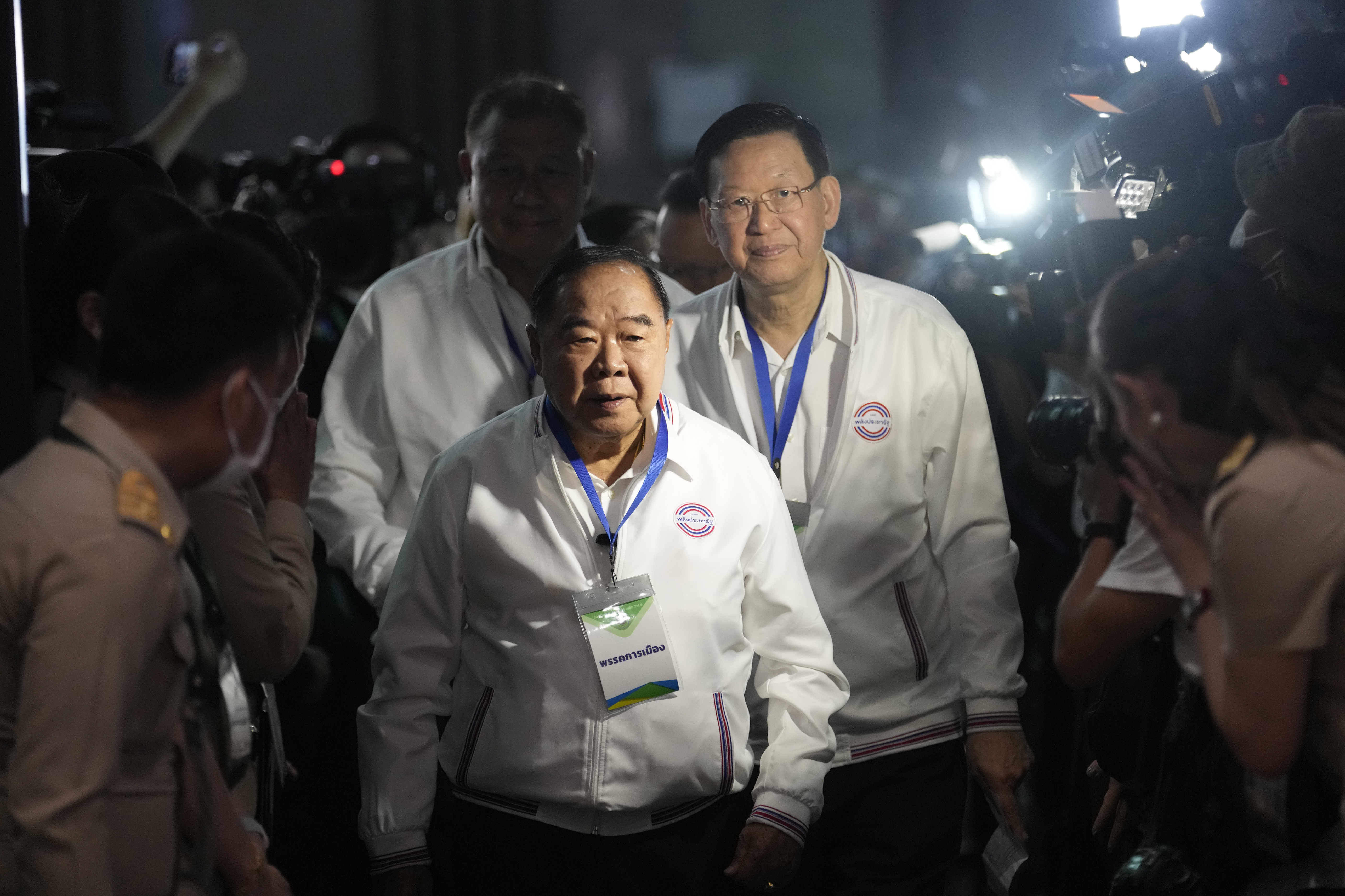 Thai Deputy Prime Minister and the prime minister candidate of the Palang Pracharath Party, Prawit Wongsuwan. He is wearing a white shirt with the party logo and is being followed by party officials. He has a lanyard round his neck.