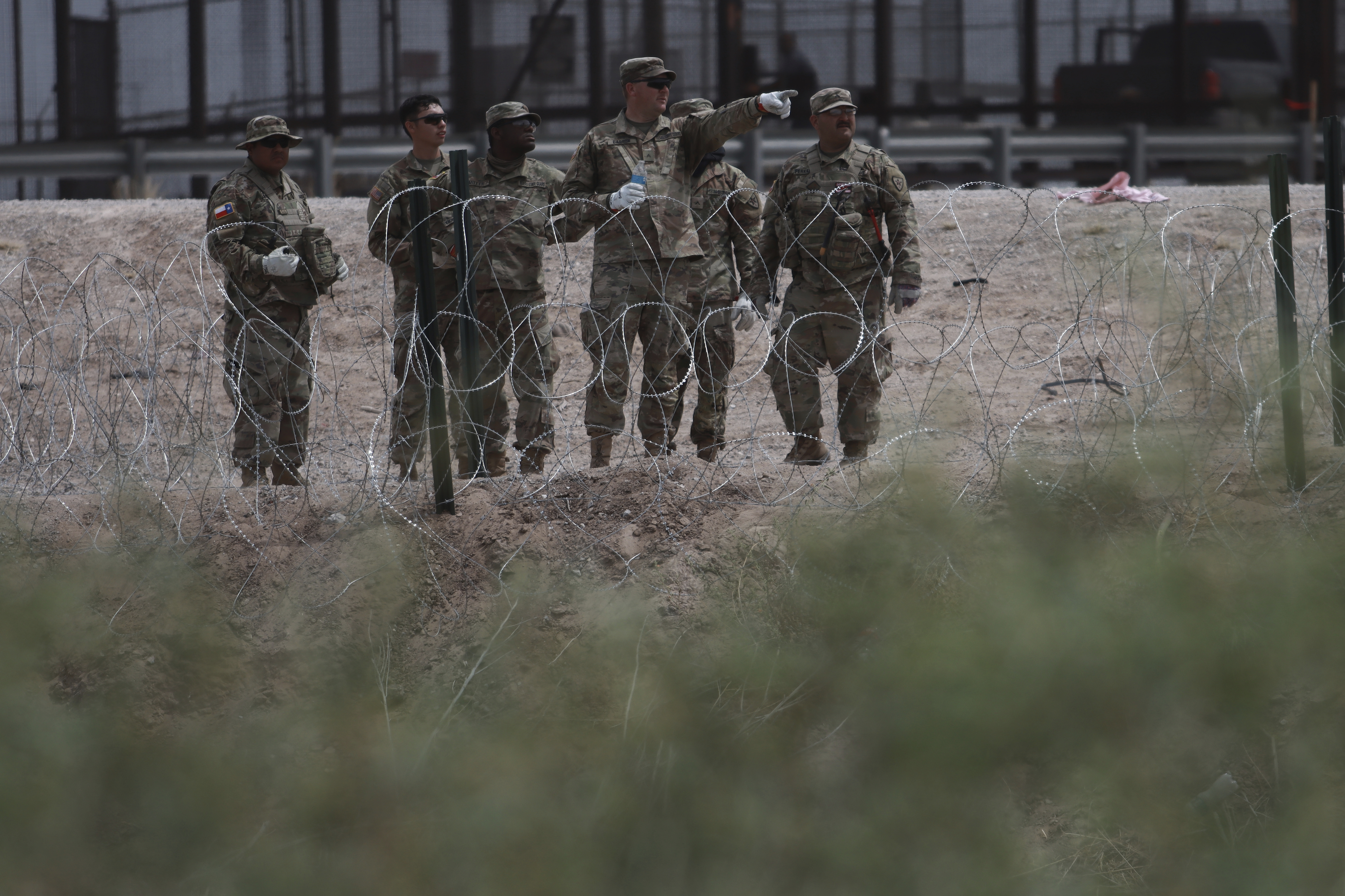 Texas National Guard members install a barbed-wire barrier at the border with Mexico