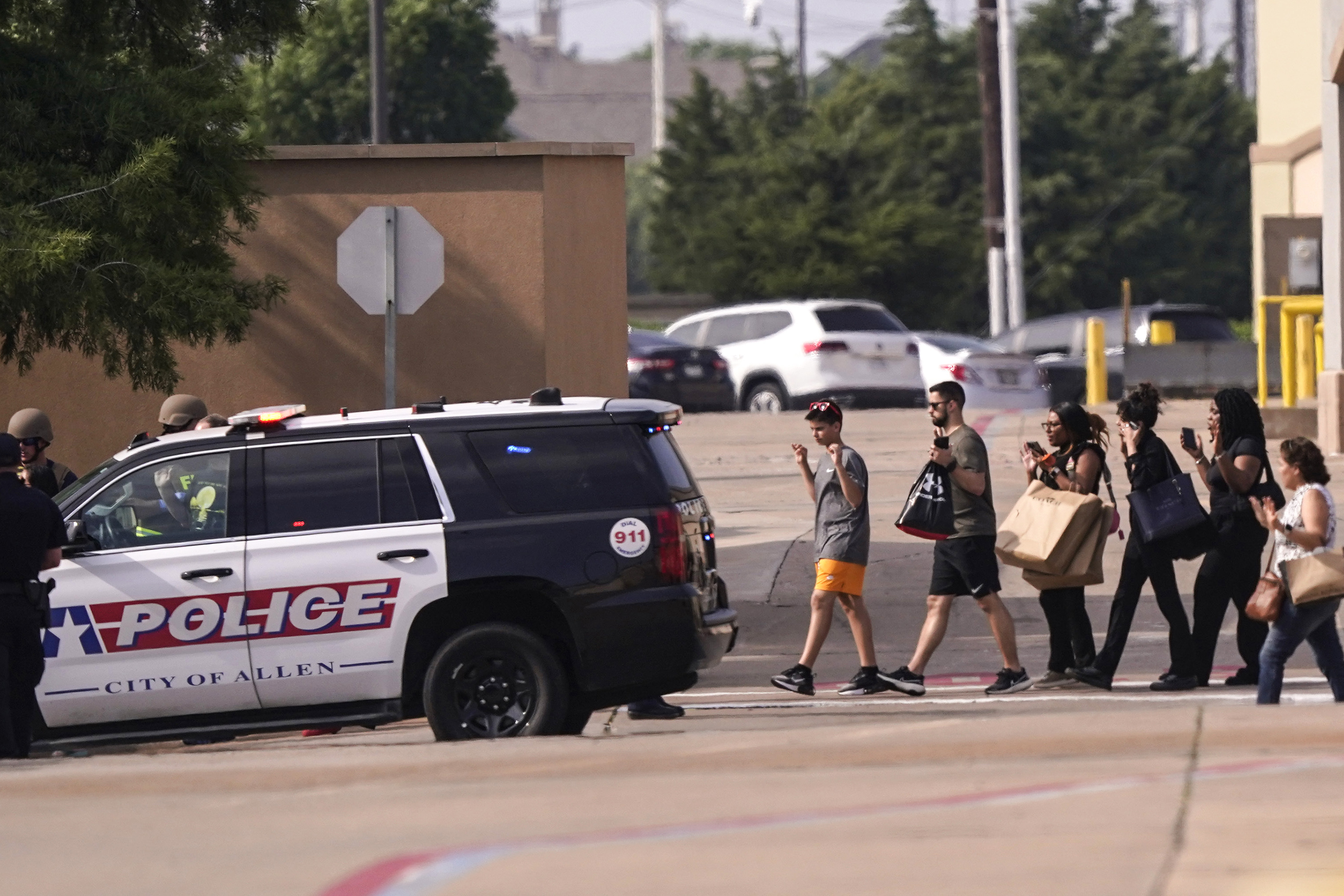 People raise their hands as they leave a shopping center following reports of a shooting