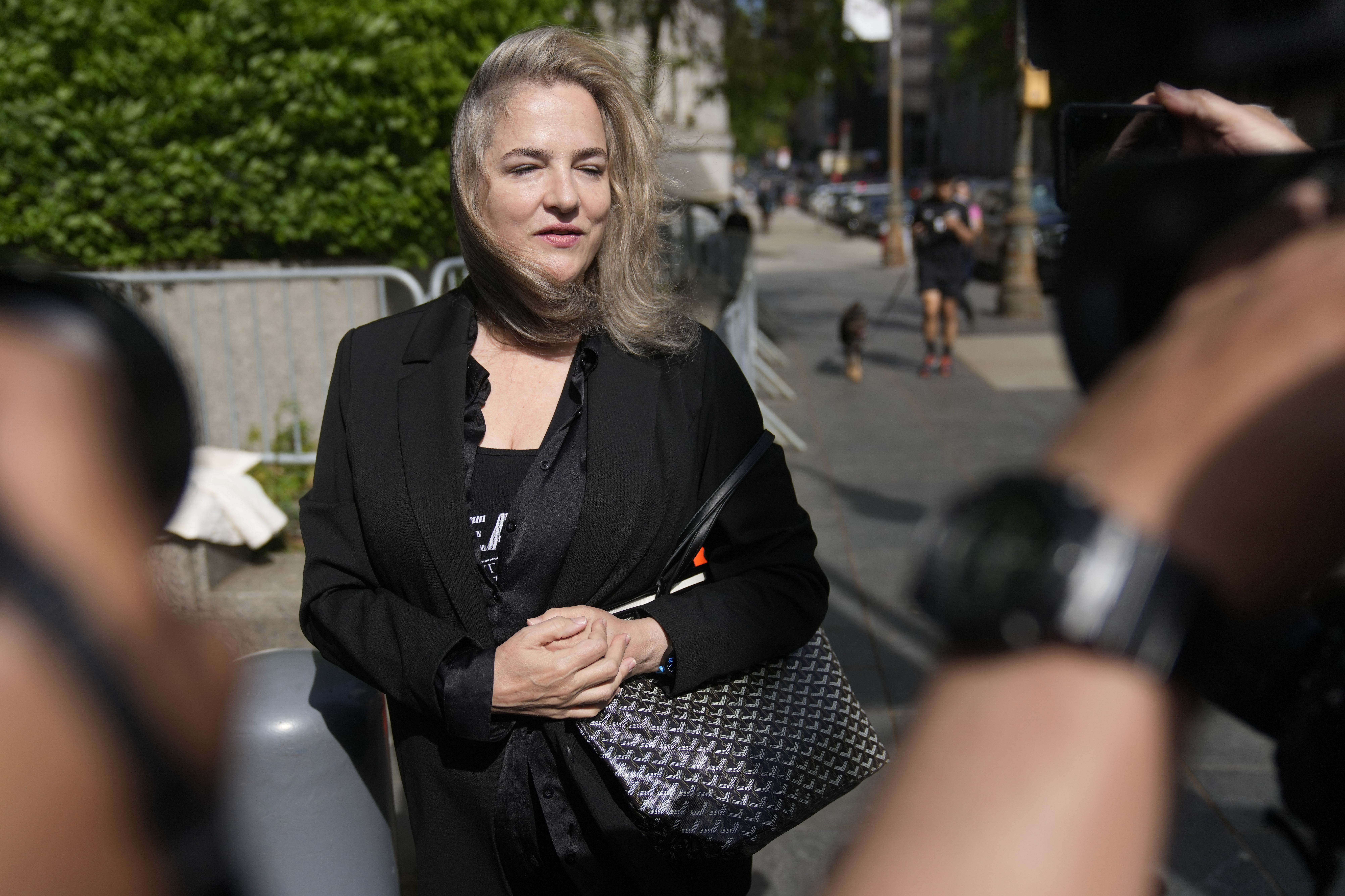 A blonde woman, dressed all in black, is photographed outside of a courthouse