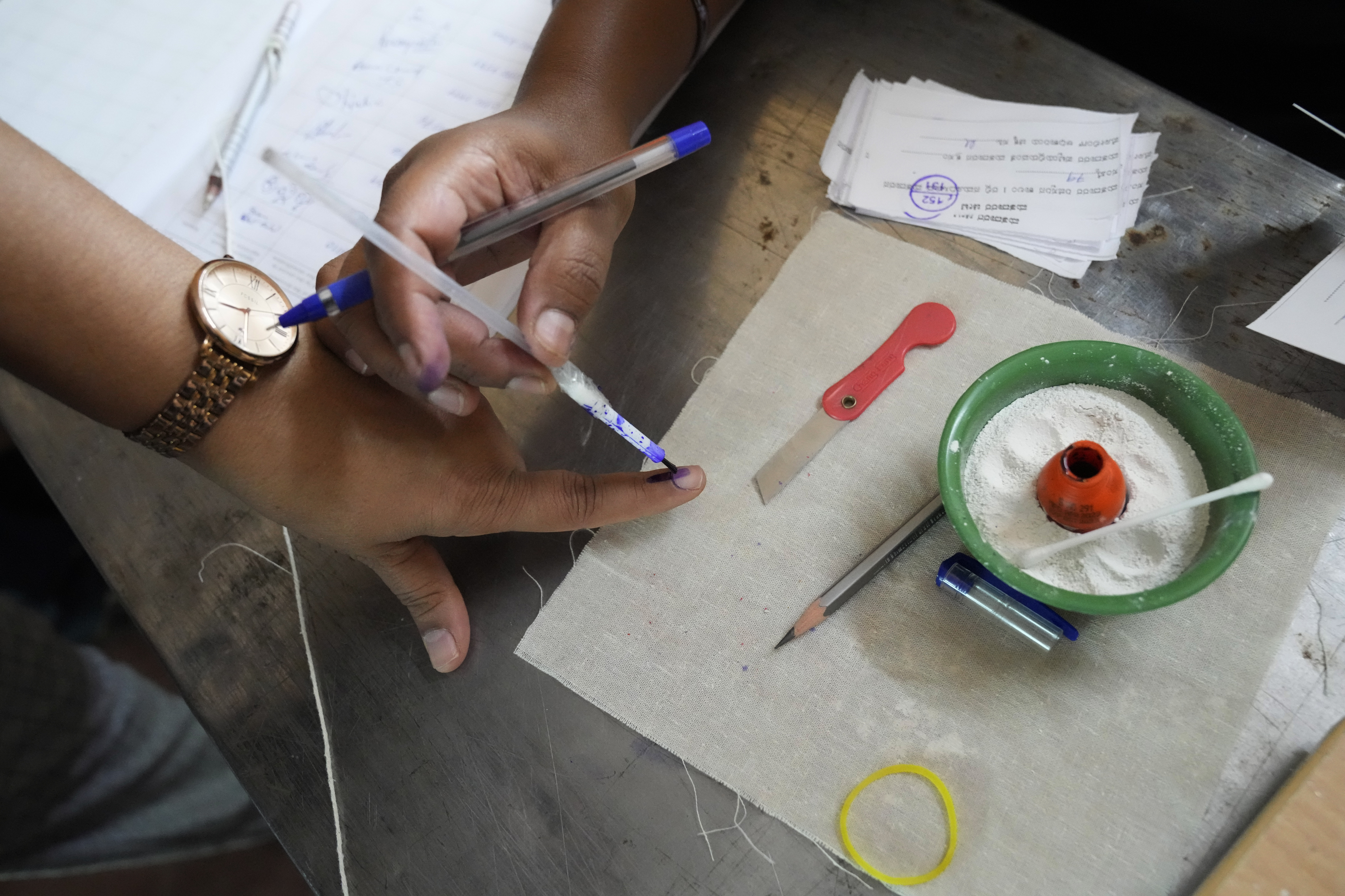 A polling officer applies indelible ink mark on a finger of a voter before letting him to proceed to cast his vote at a polling station, in Bengaluru, India