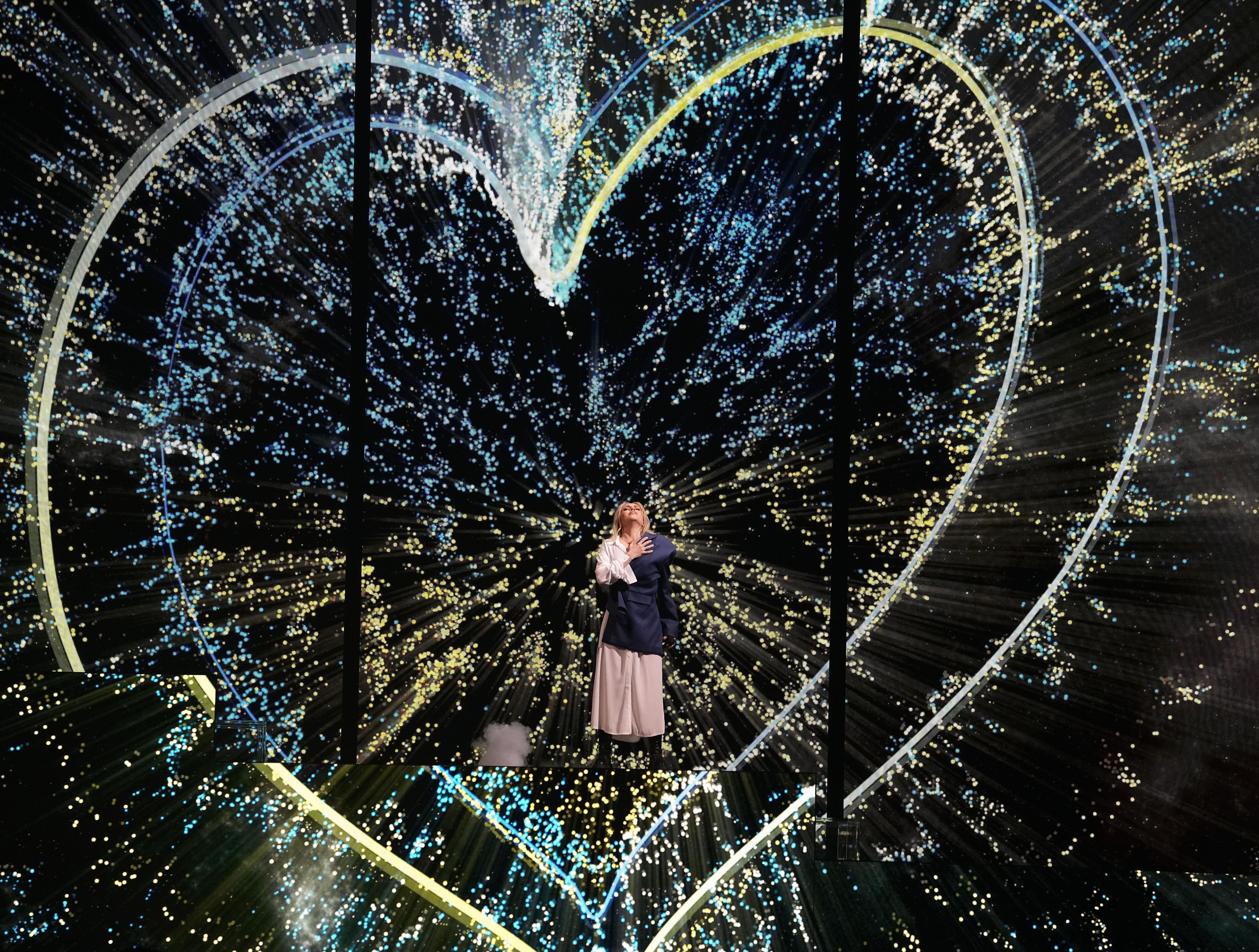 Ukrainian singer Alyosha performs in front of two handdrawn hearts in the blue and yellow of Ukraine