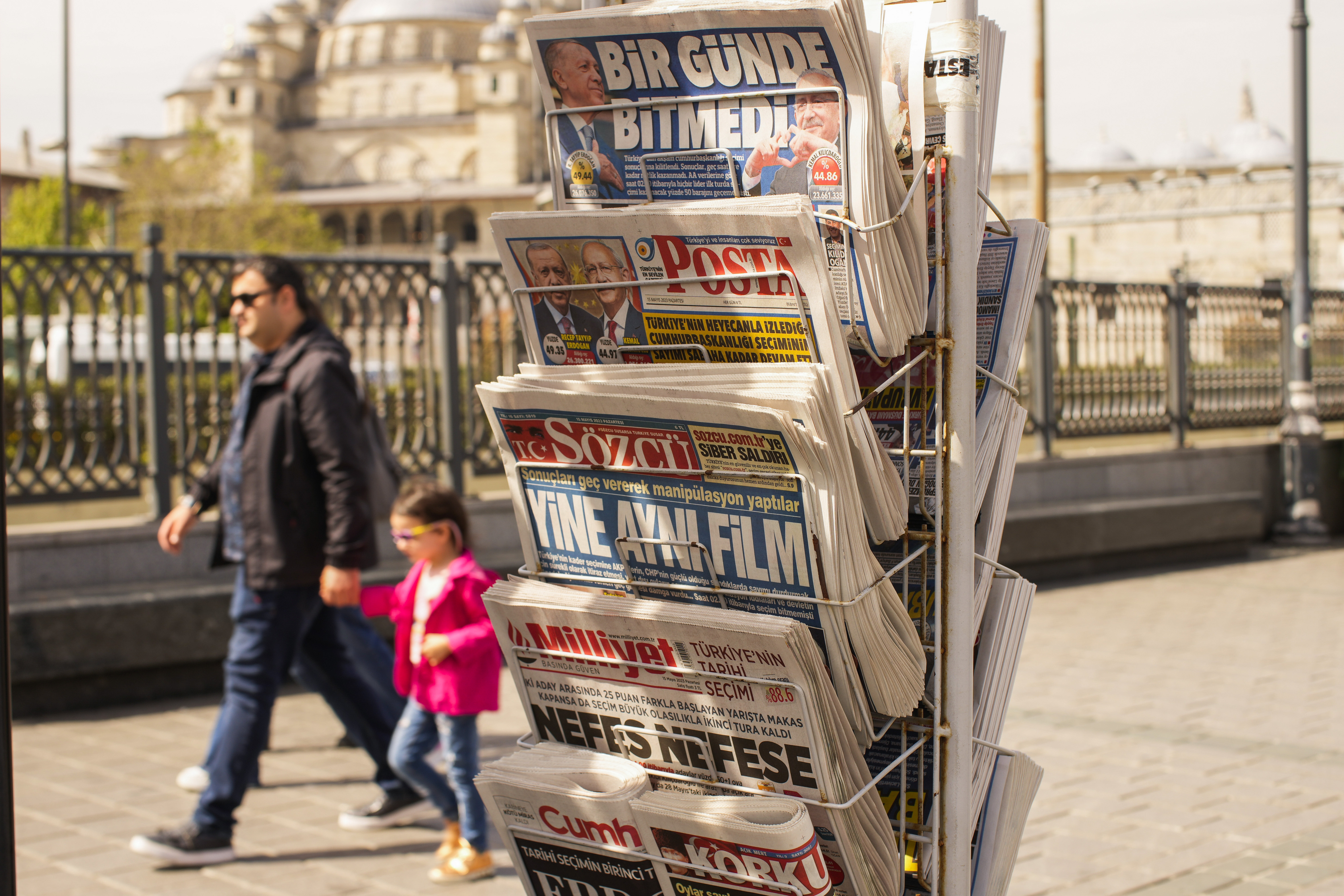 People walk past a rack with Turkish newspapers