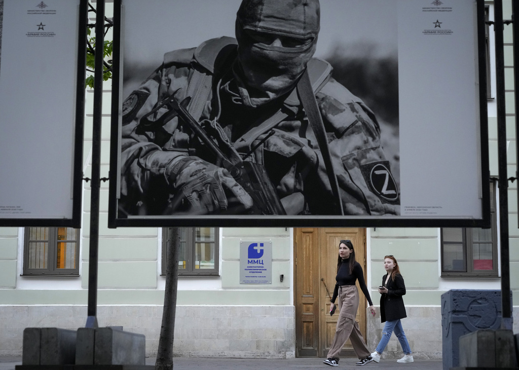People walk past a street photo exhibition entitled "The eyes of the undefeated Donbas", by the Ministry of Defense of Russia showing participants of events in Ukraine, in St. Petersburg, Russia, Monday, May 15, 2023. (AP Photo/Dmitri Lovetsky)