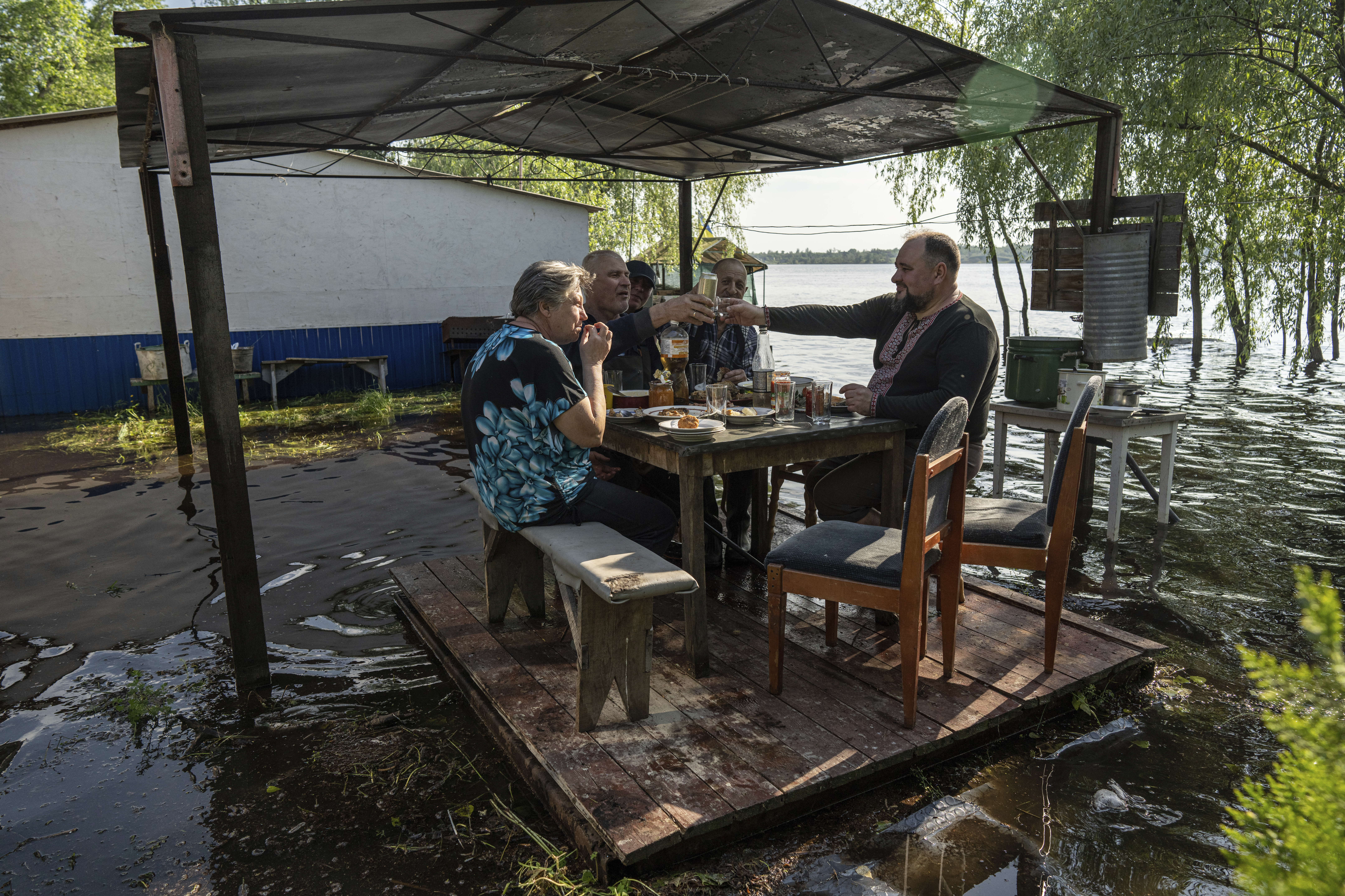 Lyudmila Kulachok, 54, left, with her family have dinner at the flooded courtyard of their house 
