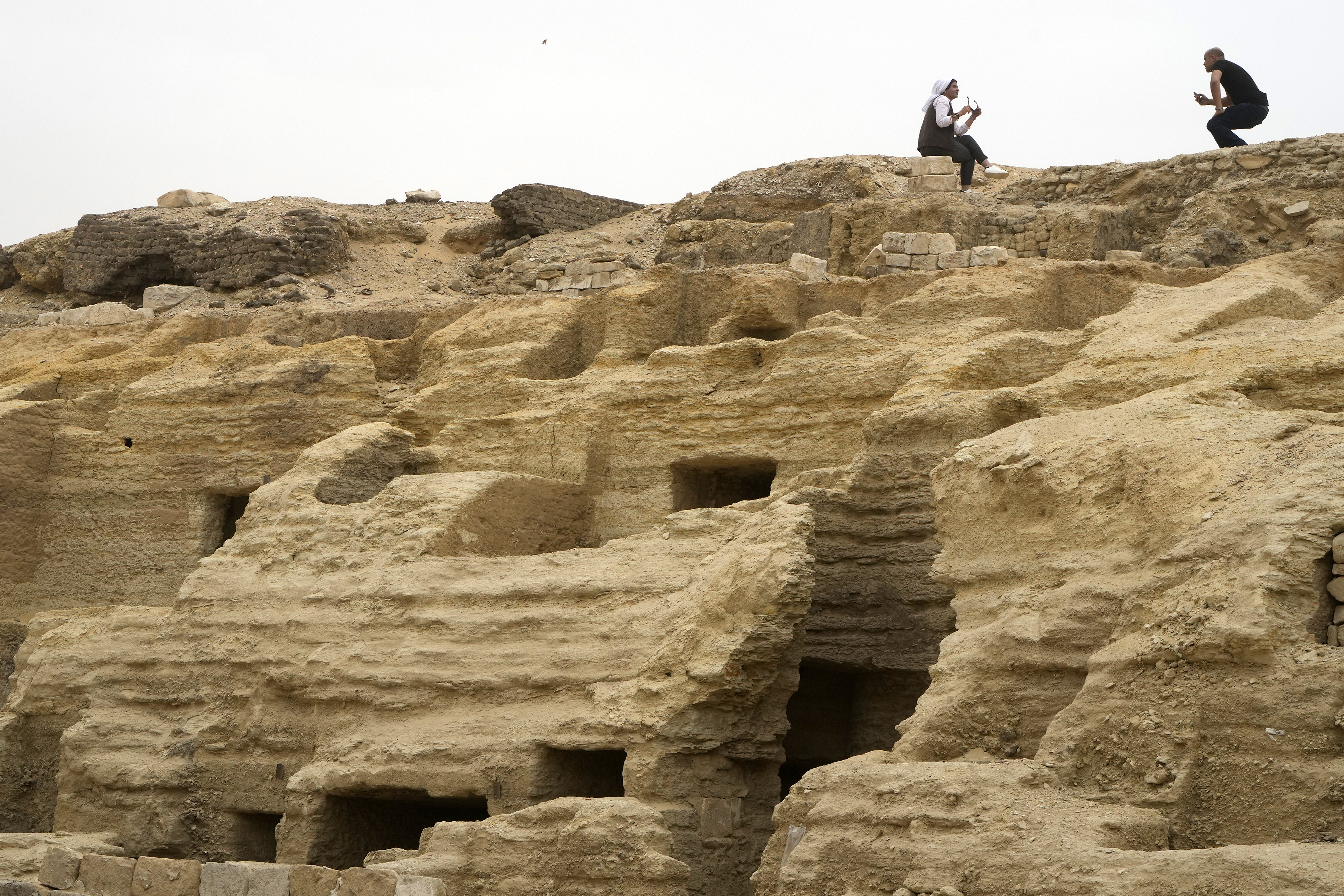 Visitors pose for pictures on top of recently unearthed ancient embalming workshops