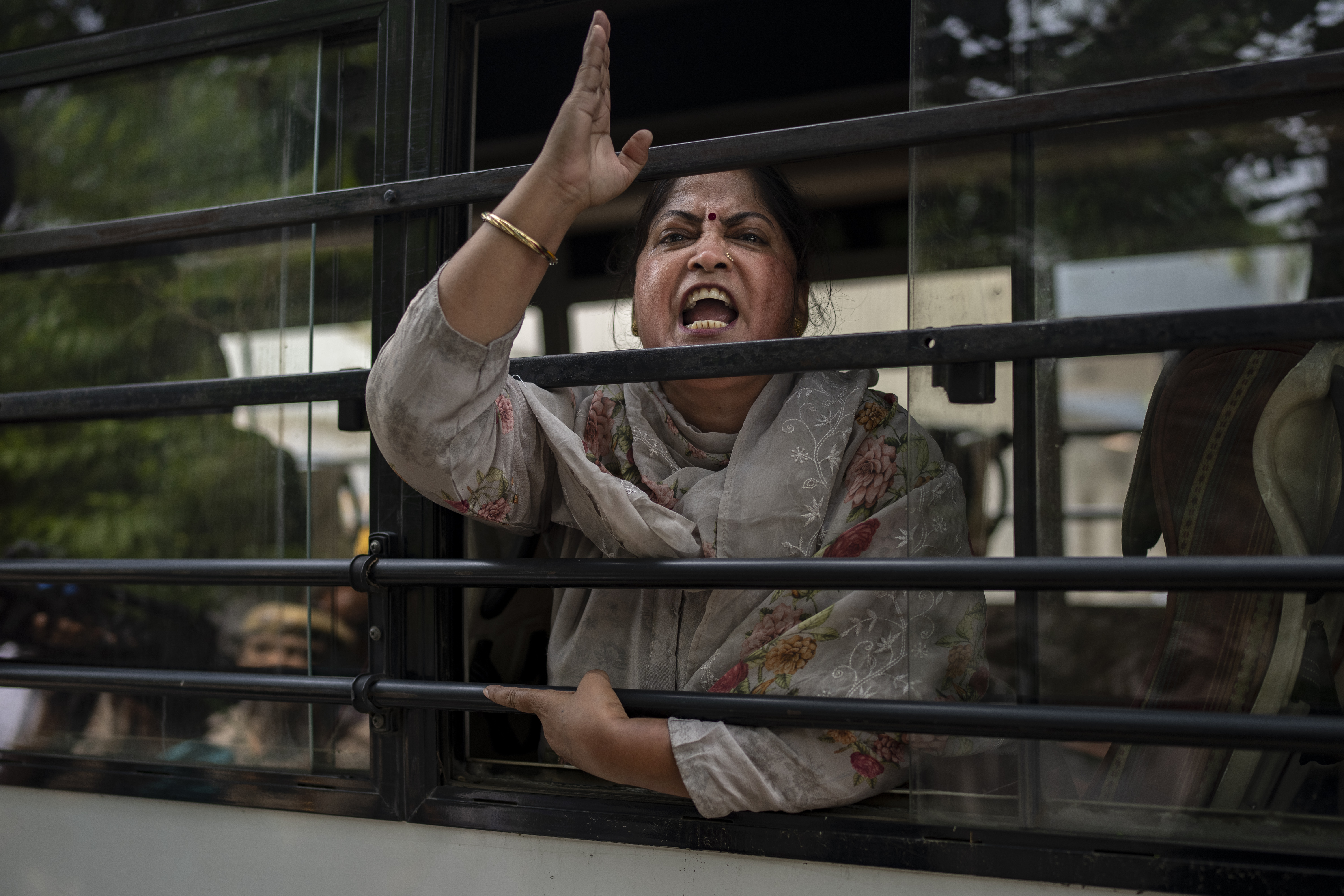 An activist who had come to support protesting wrestlers shouts slogans as she is detained by the police