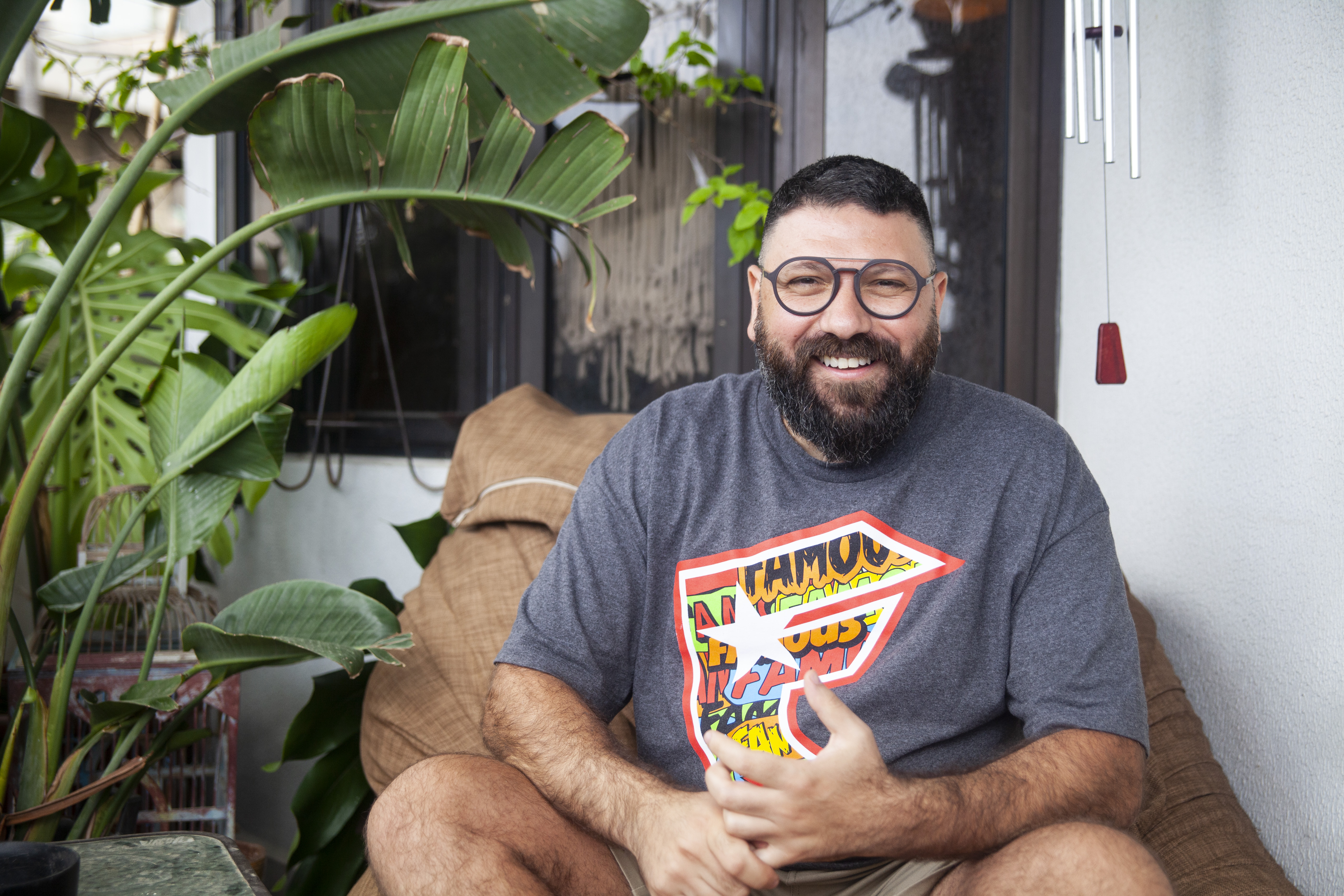 A photo of Chadi smiling sitting next to a plant.
