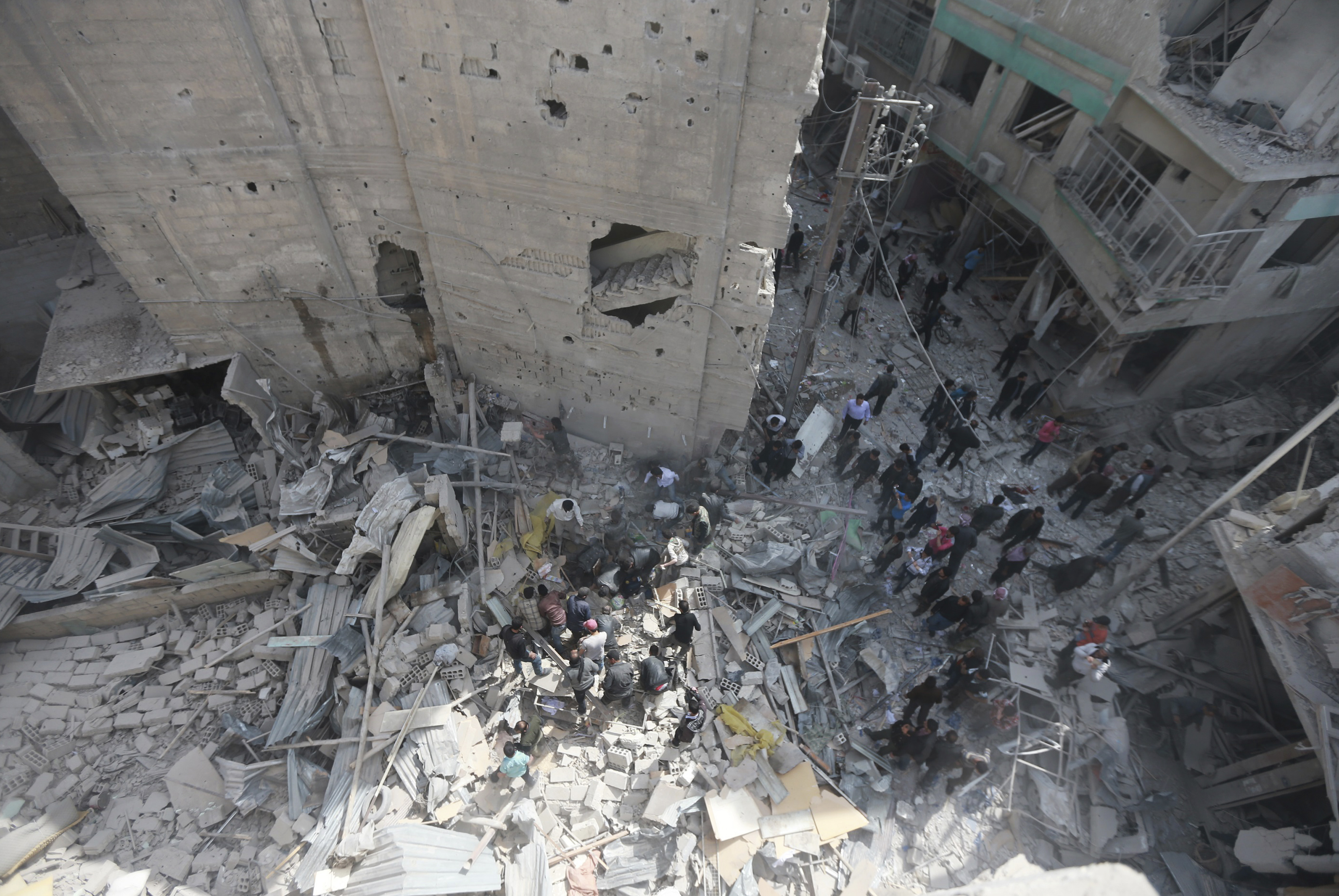 People gather at a site hit by what activists said was a warplanes attack by forces loyal to Syrian President Bashar al-Assad in the Duma neighbourhood of Damascus April 13, 2014
