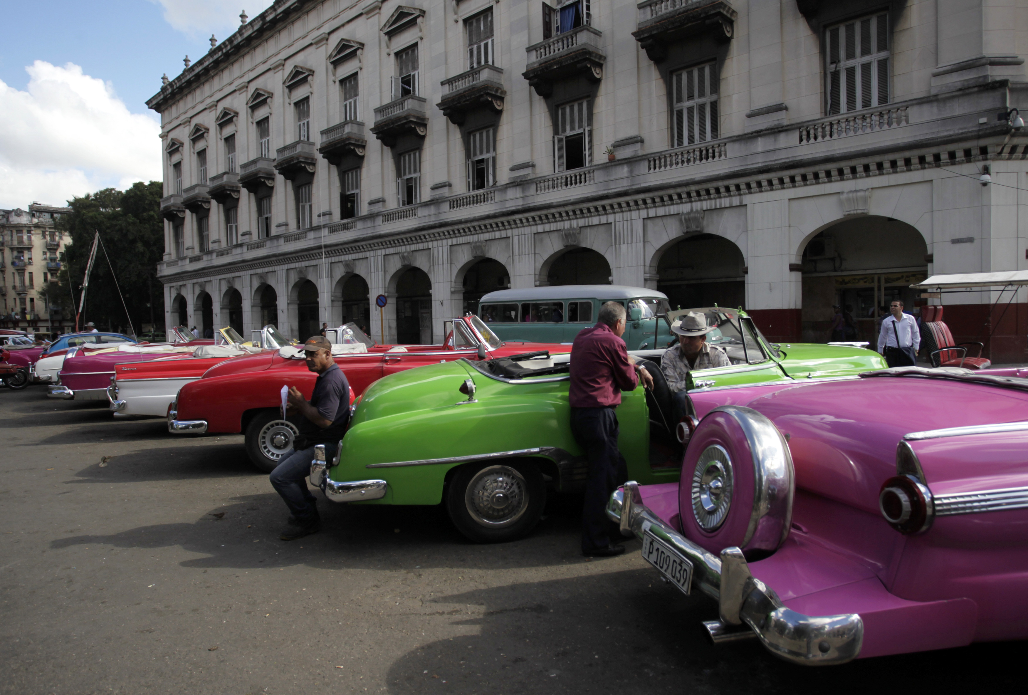 Drivers stand near their vintage cars waiting for clients in Havana December 17, 2014. Stunned Cubans celebrated an apparent end to decades of conflict with the United States on Wednesday after both governments said they would restore diplomatic relations cut off in 1961. Many said they expected a restoration of ties would lead to the end of a U.S. economic embargo against Cuba, which is vilified daily in the official media and which Cubans accept as a key cause of widespread poverty on the island. REUTERS/Stringer (CUBA - Tags: POLITICS TRANSPORT SOCIETY BUSINESS EMPLOYMENT)