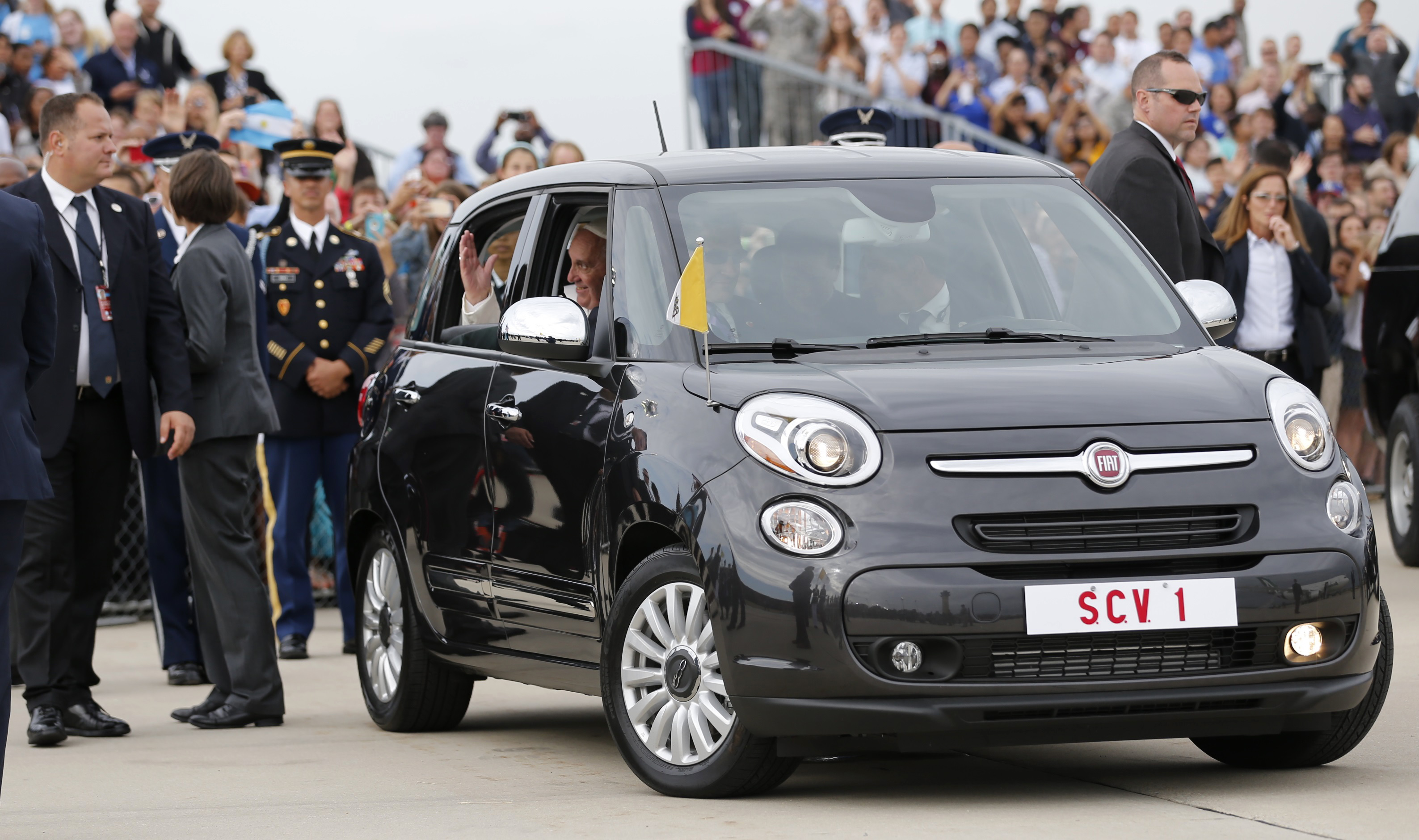 Pope Francis waves as he is driven away in a Fiat 500 model after arriving in the United States at Joint Base Andrews outside Washington