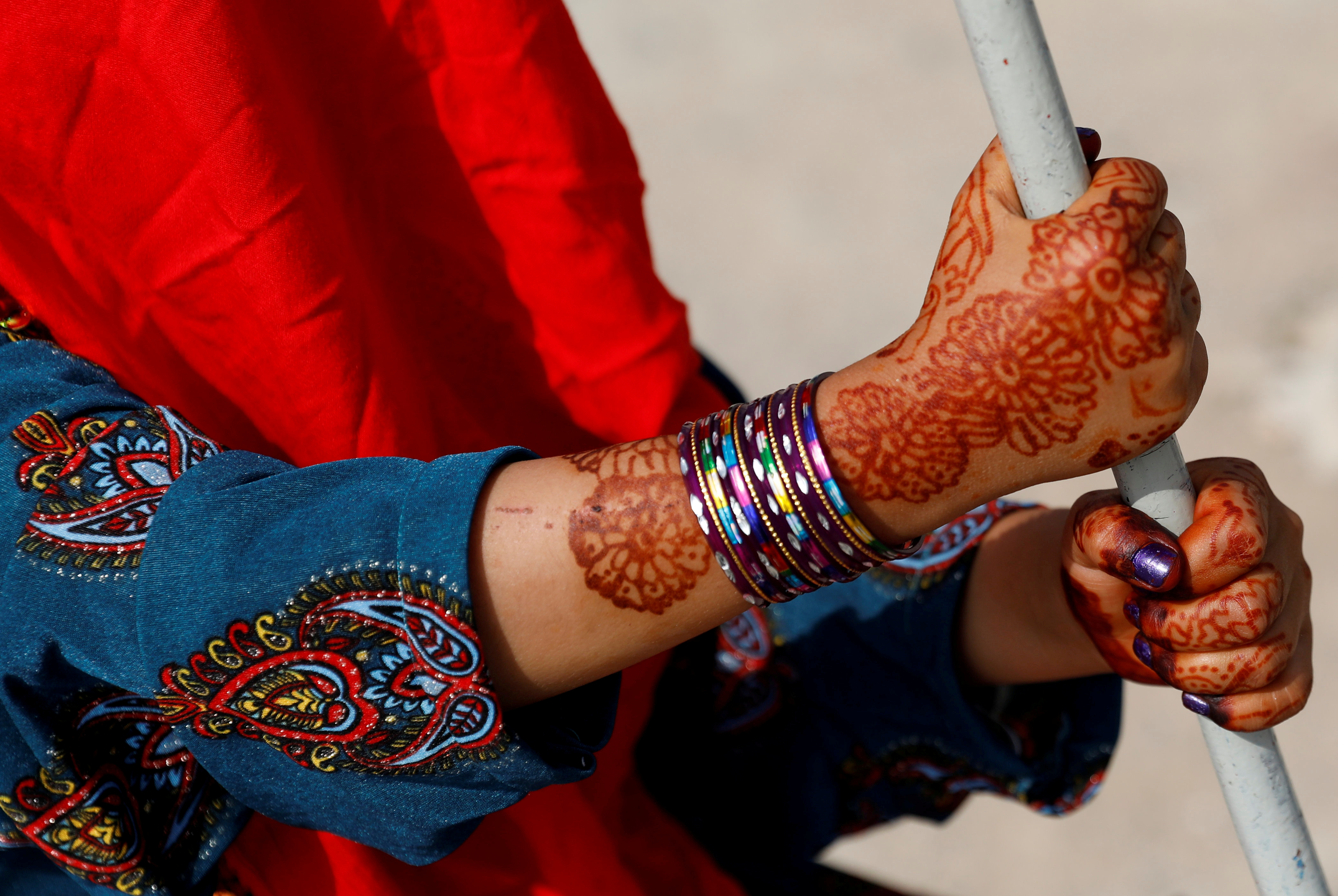An Afghan girl with henna patterns on her hands rides on a swing during the first day of the Muslim holiday of the Eid al-Adha, in Kabul, Afghanistan 