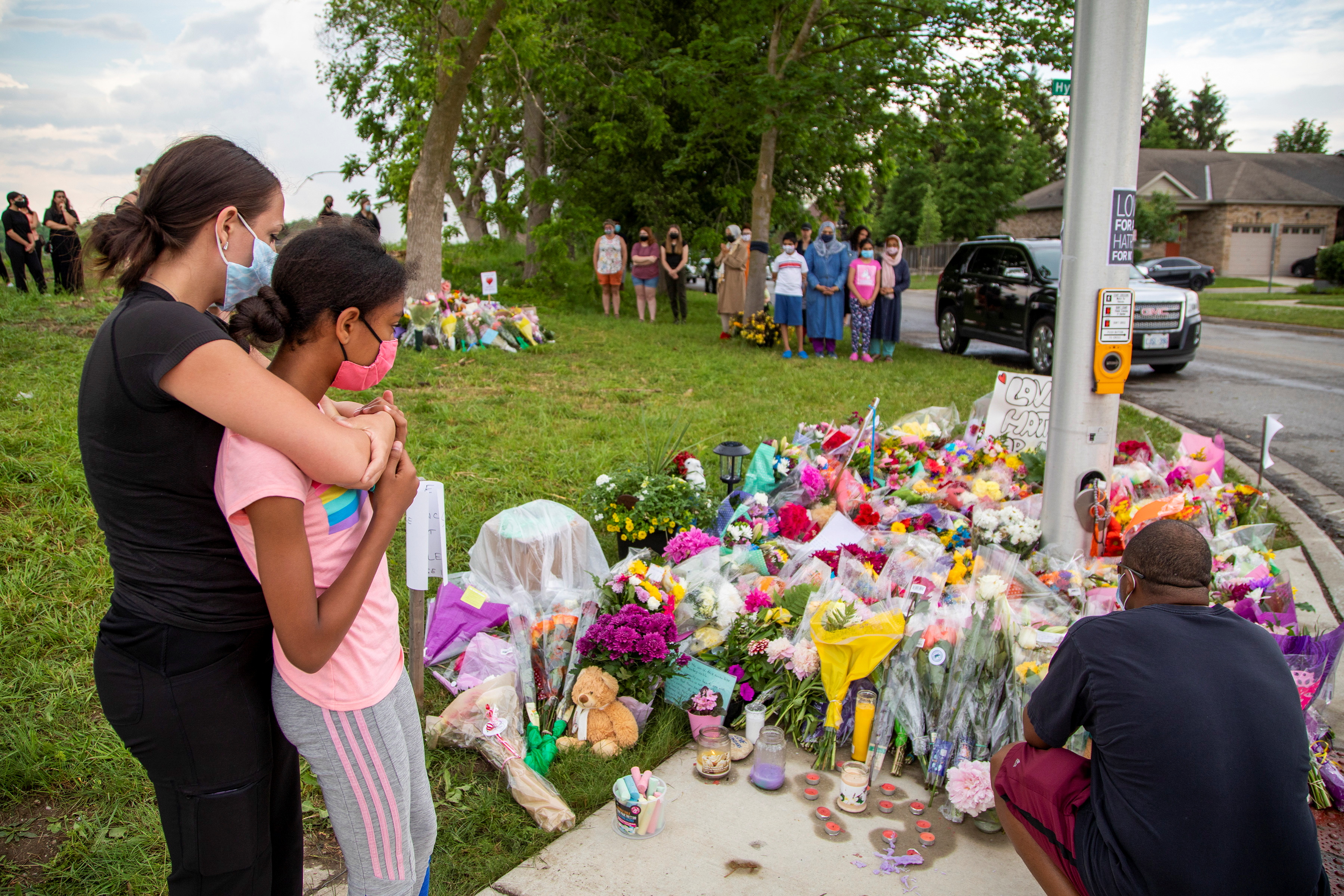 People hug at a makeshift memorial to a Muslim family that was fatally run down in London, Ontario, Canada in 2021
