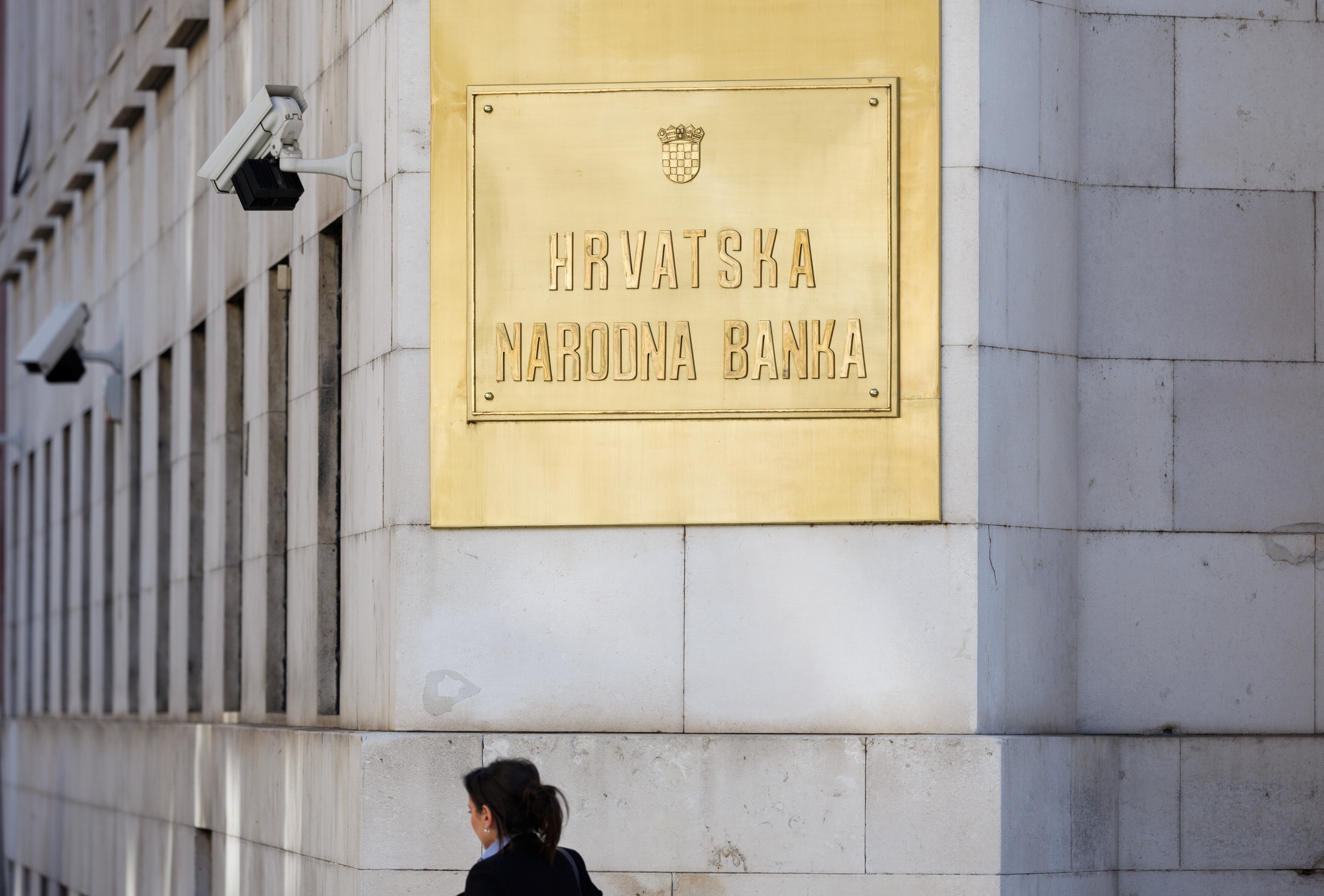 A woman passes a sign on the building of Croatian National Bank in downtown of Zagreb, Croatia, February 7, 2022.