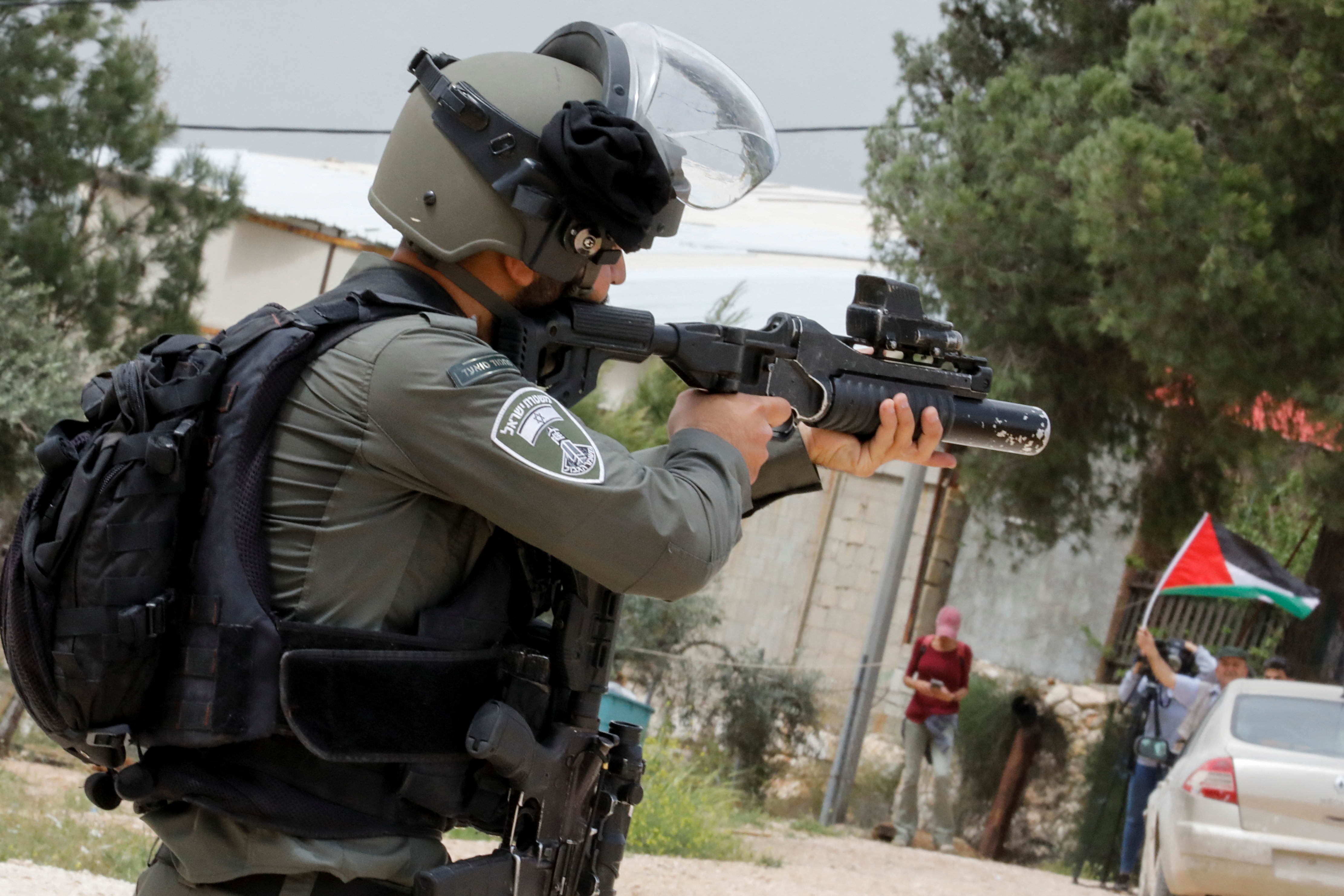 An Israeli border police officer aims his weapon at Palestinian demonstrators protesting against Israeli settlements near Nablus in the Israeli-occupied West Bank, April 10, 2023. REUTERS/Raneen Sawafta