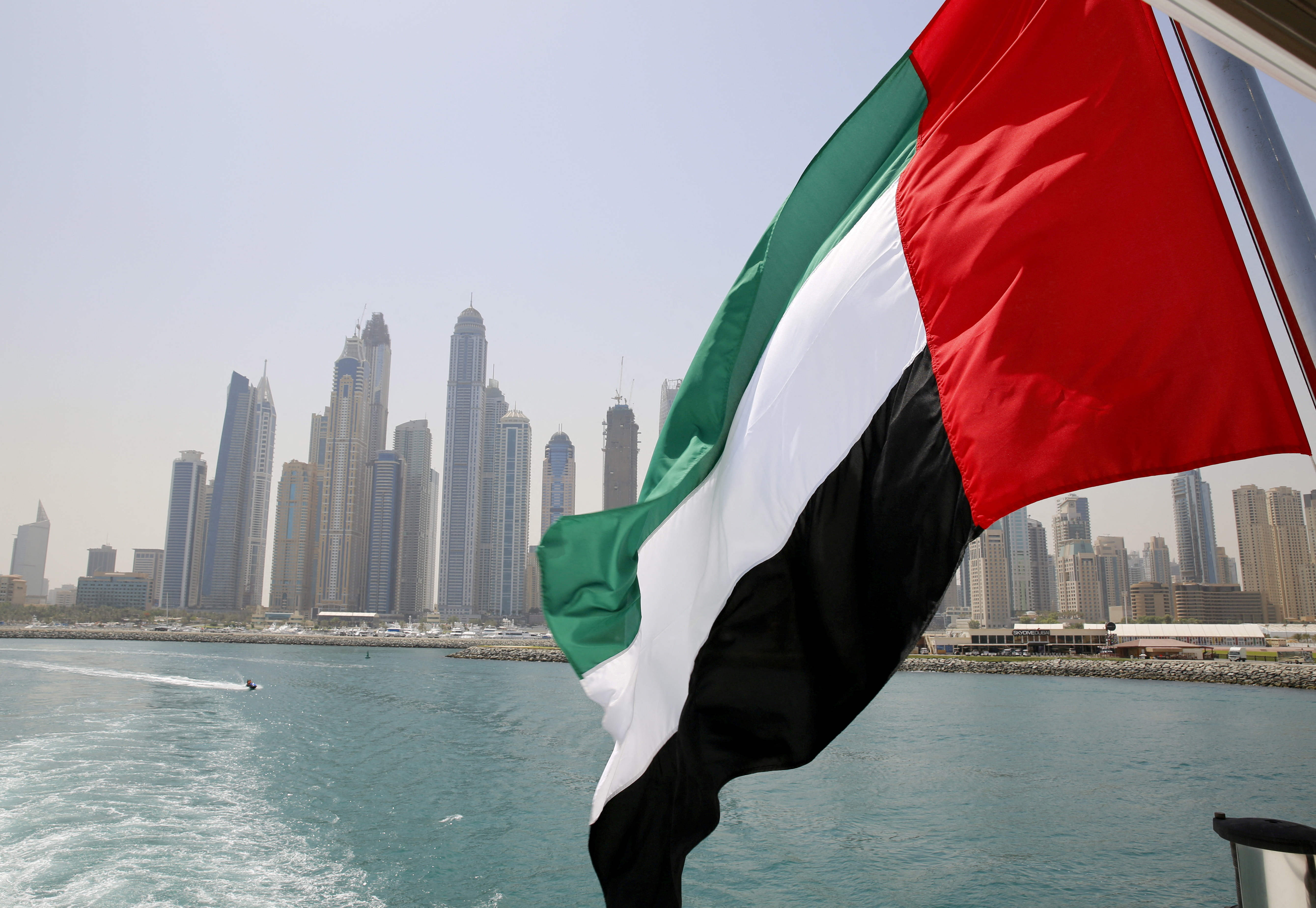The UAE flag flies over a boat at Dubai Marina, Dubai, United Arab Emirates