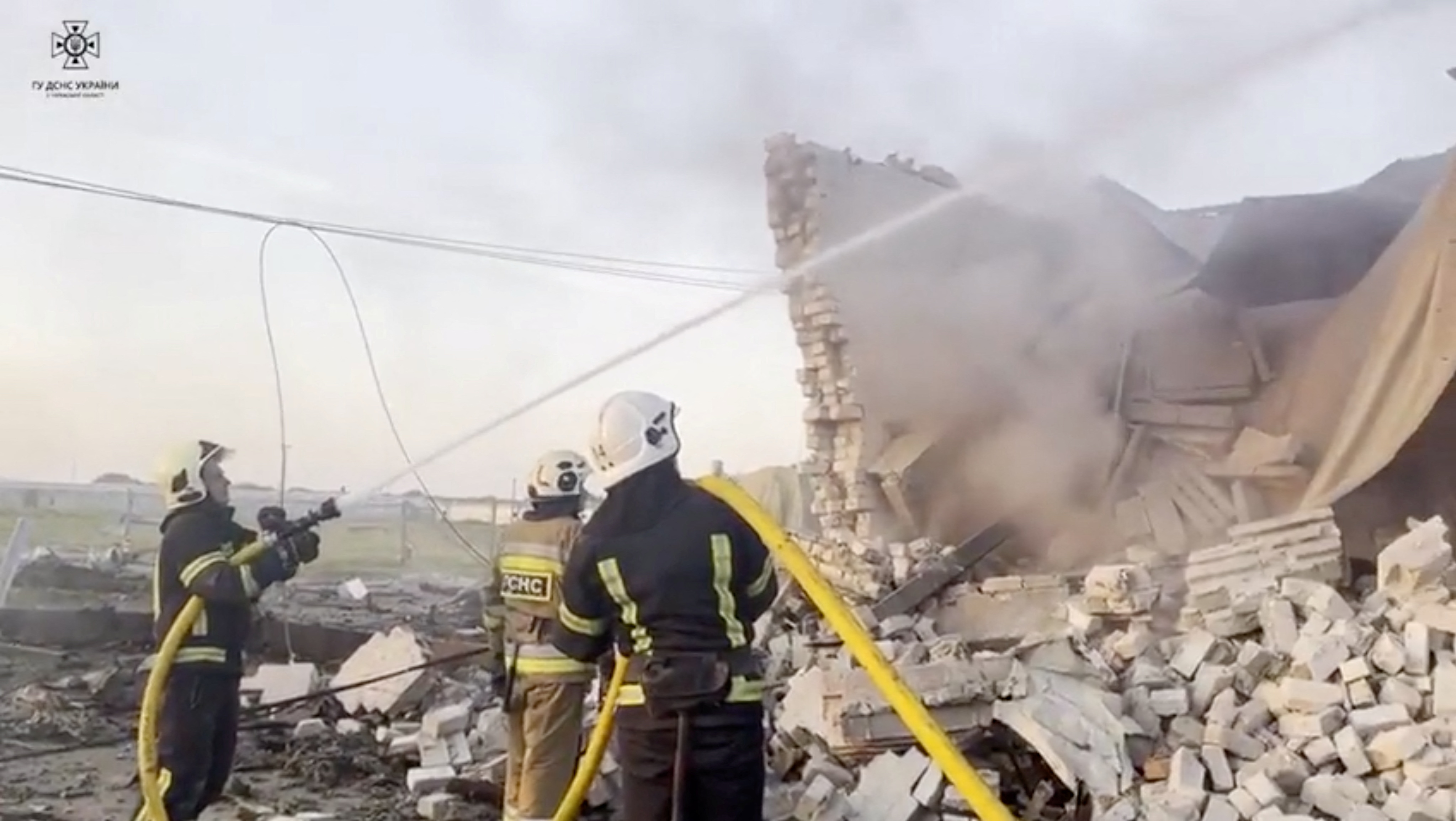Firefighters work at a site of a damaged building