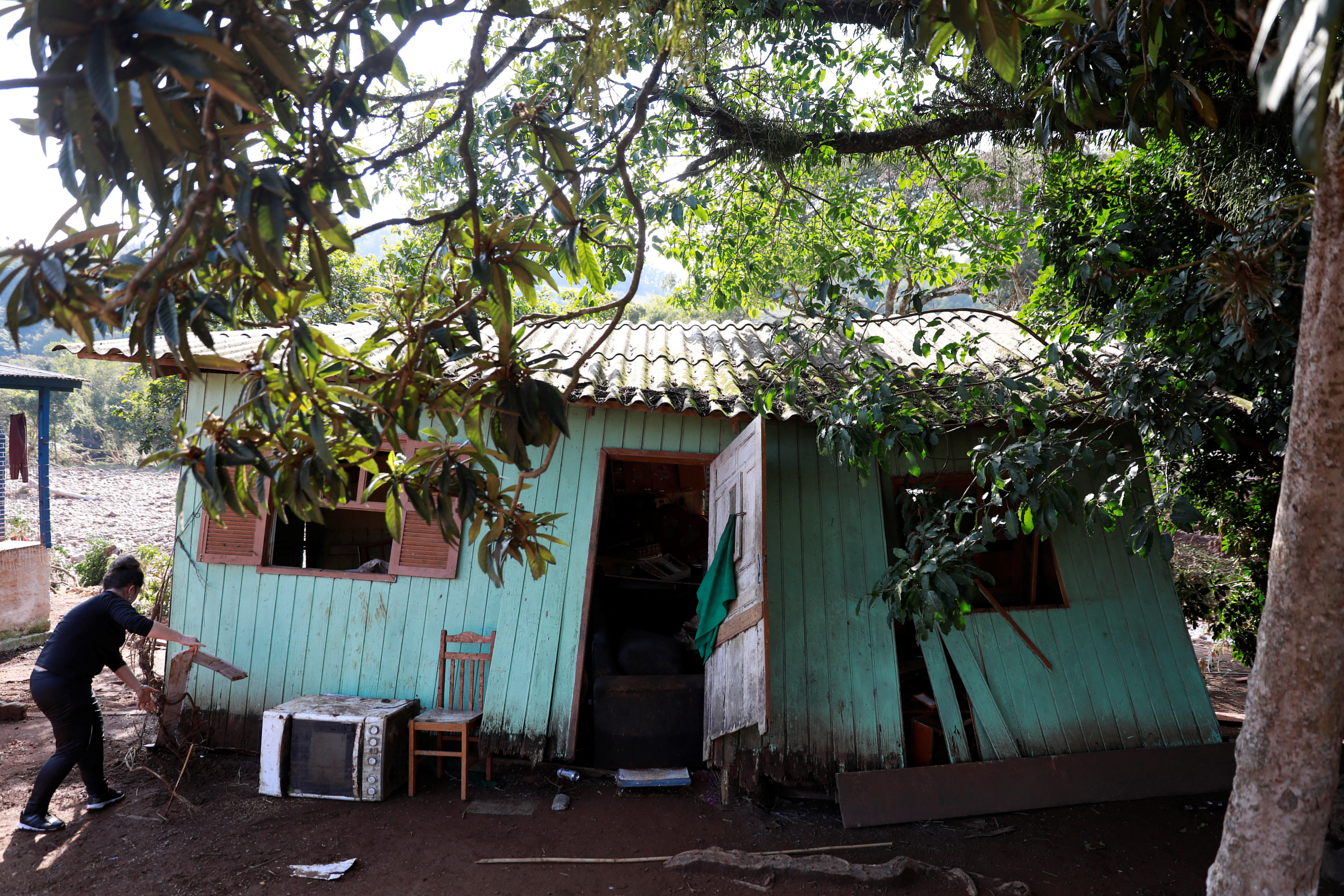 A woman retrieves her belongings from her damaged house after flooding due to heavy rains following an extratropical cyclone, in Caraa