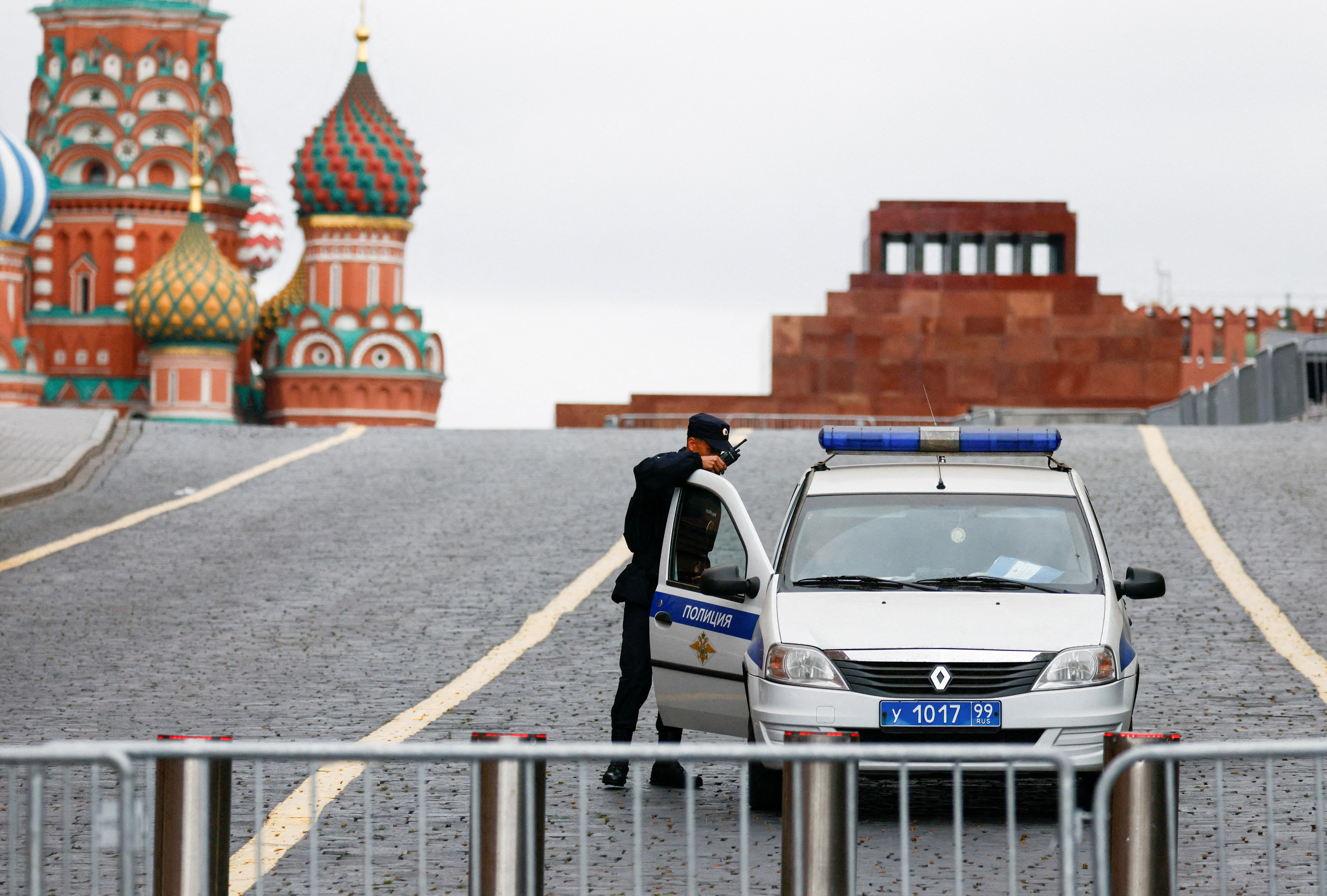A view of Red Square and St Basil's Cathedral. The square is fenced off and there is a police car behind the barrier. An officer is by the car door.