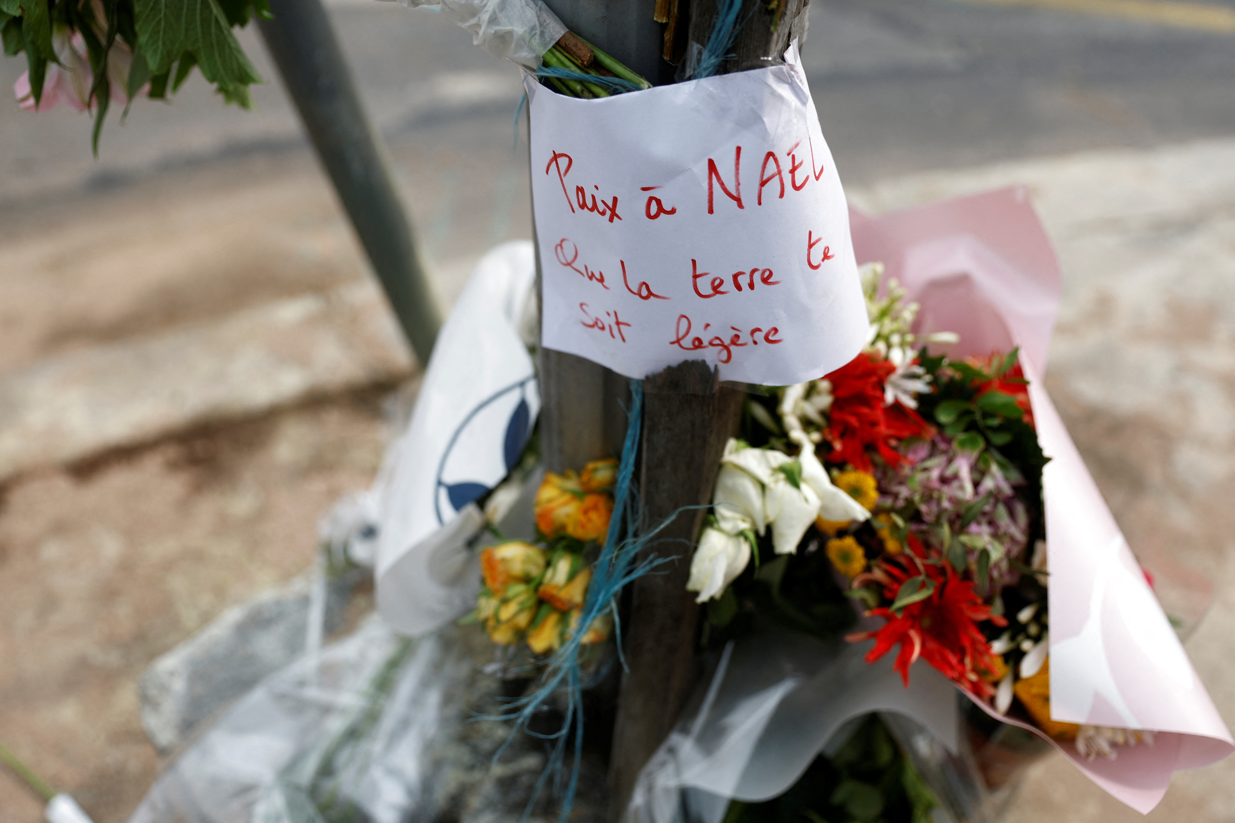 Flowers are seen at the site where Nahel was killed by a French police officer during a traffic stop. The message reads 'Peace to Nael, may the earth be light to you'