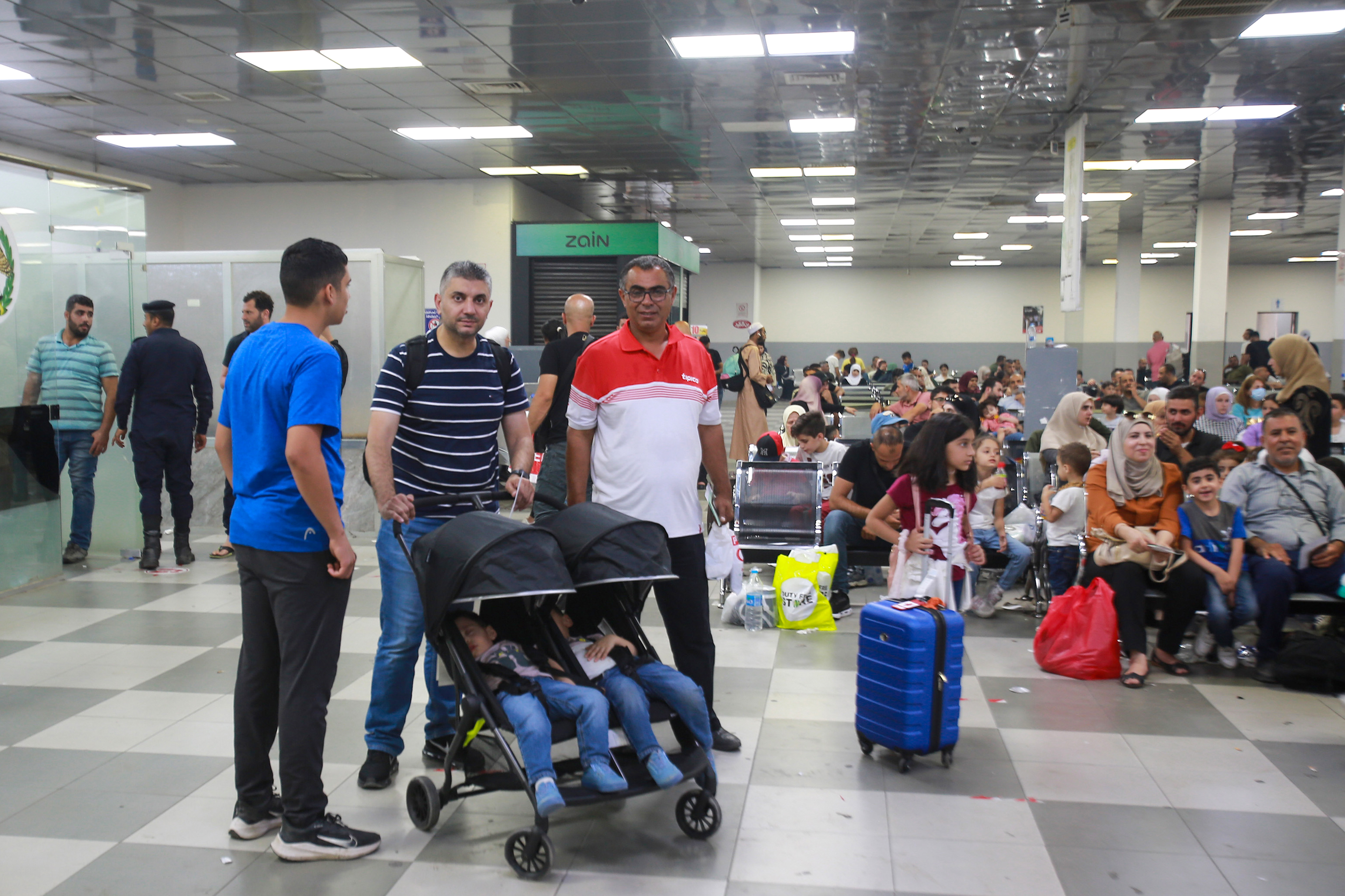 Passengers sit in a waiting room on the Jordanian side of the King Hussein Bridge (also known as Allenby Bridge) crossing between the West Bank and Jordan on July 19, 2022. - The border crossing, which serves as a border crossing between Israel and Jordan mainly for the Palestinians and foreign tourists, has witnessed an issue with crowding with passengers stuck on the Jordanian side. (Photo by Khalil MAZRAAWI / AFP)