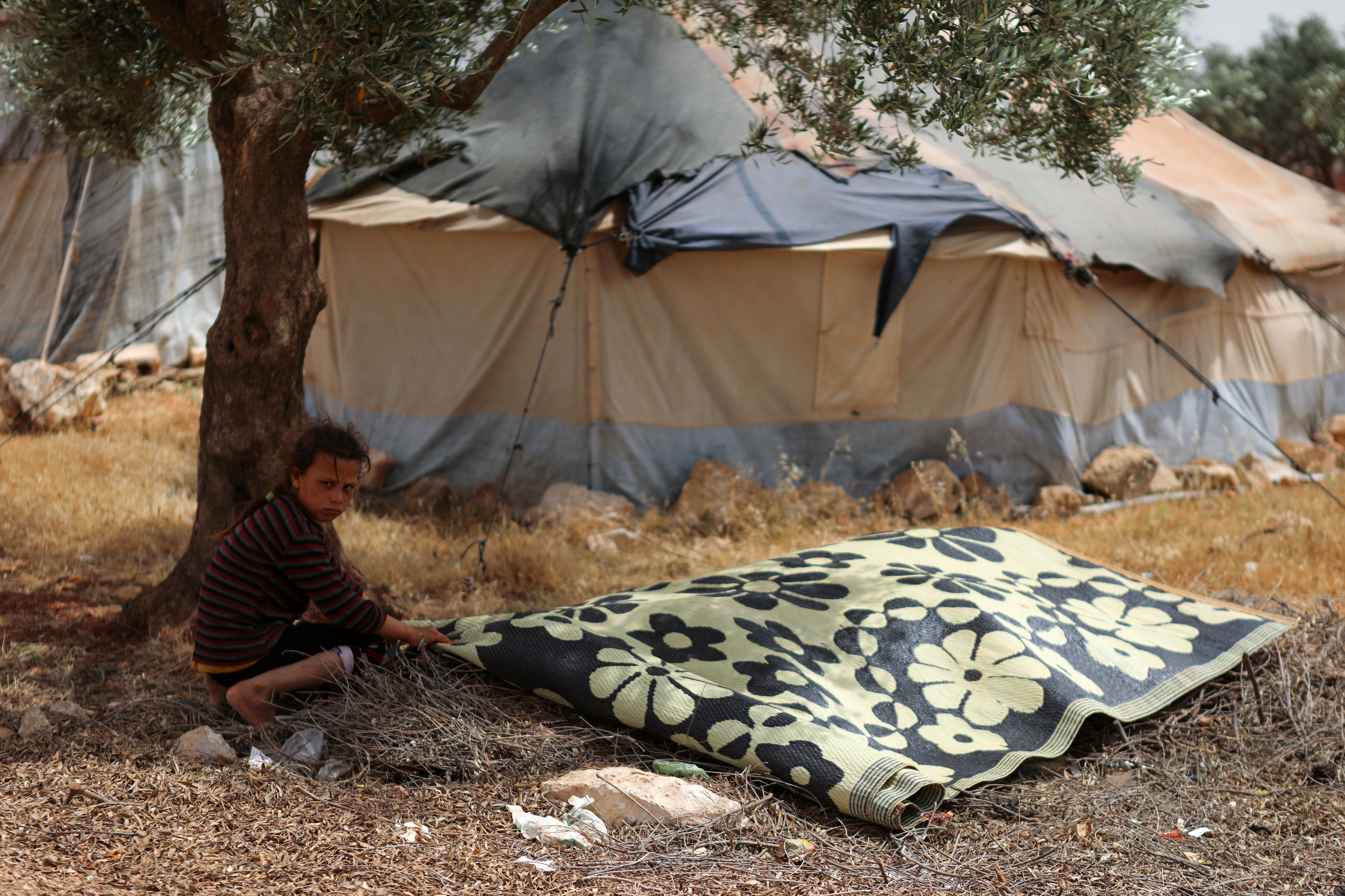 a child spreads a rug made from recycled plastic,