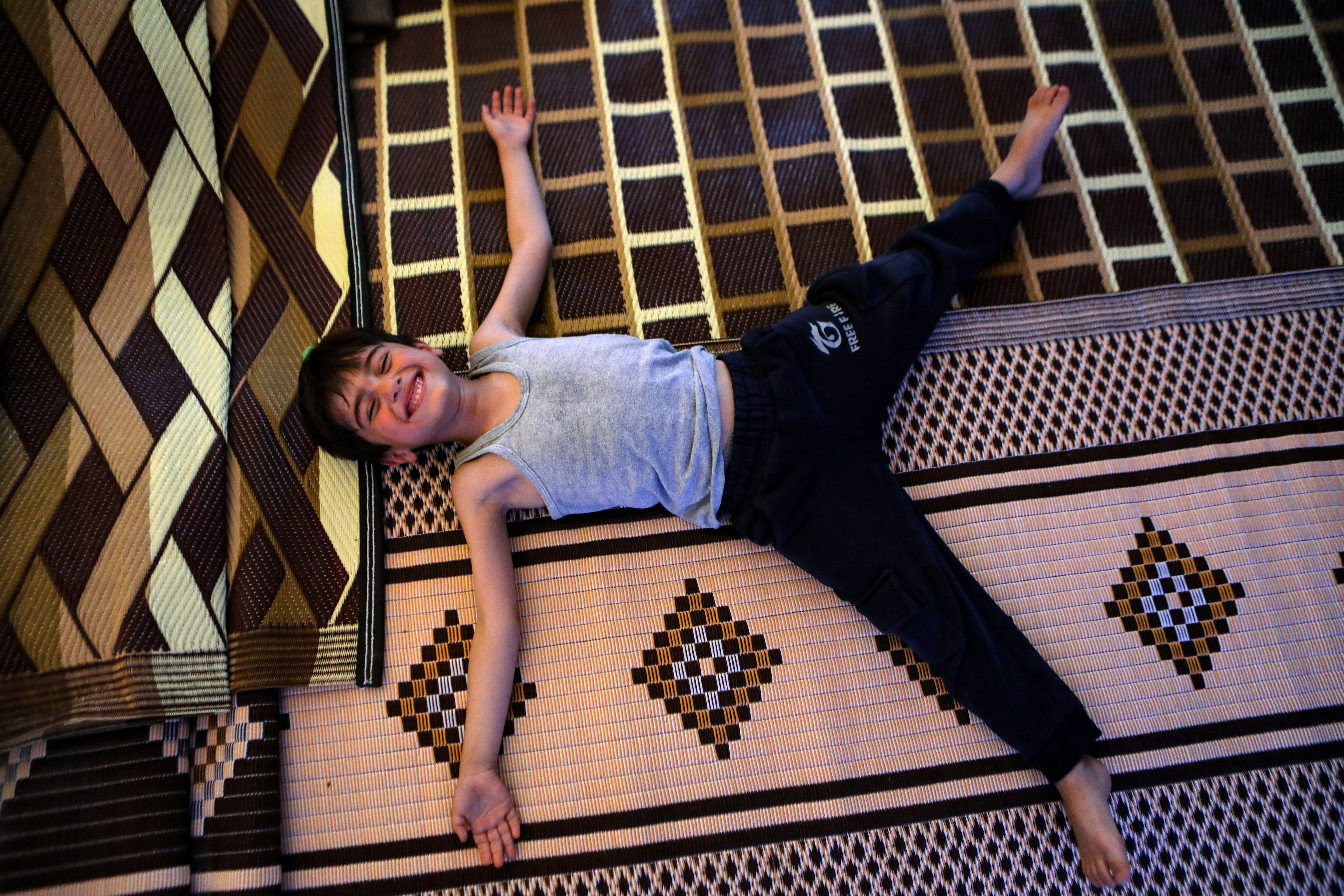 a child lies on a carpet made of recycled plastic