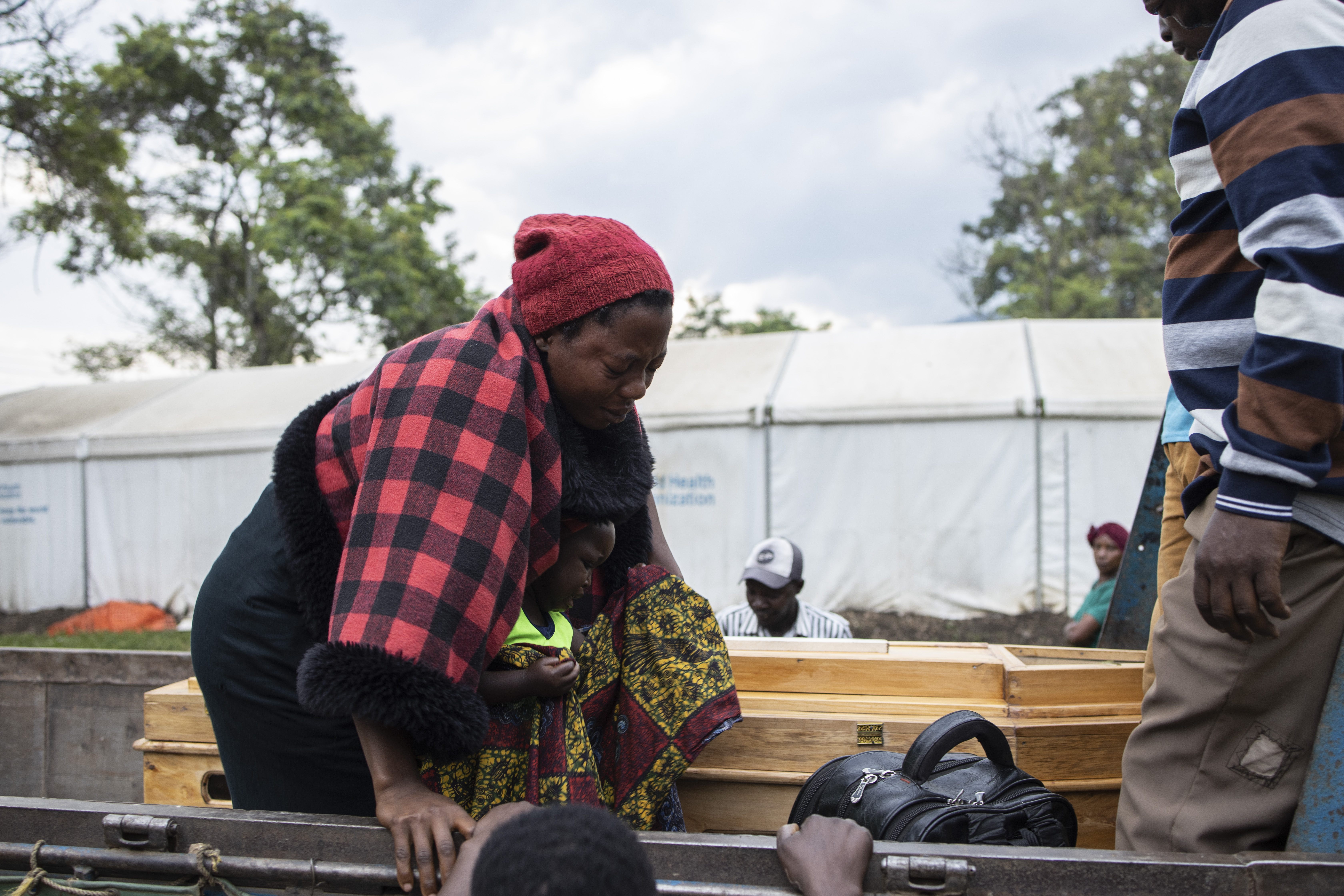The relative of a victim of the Mpondwe Lhubiriha Secondary School mourns as she leans towards a casket outside the Bwera General Hospital Mortuary
