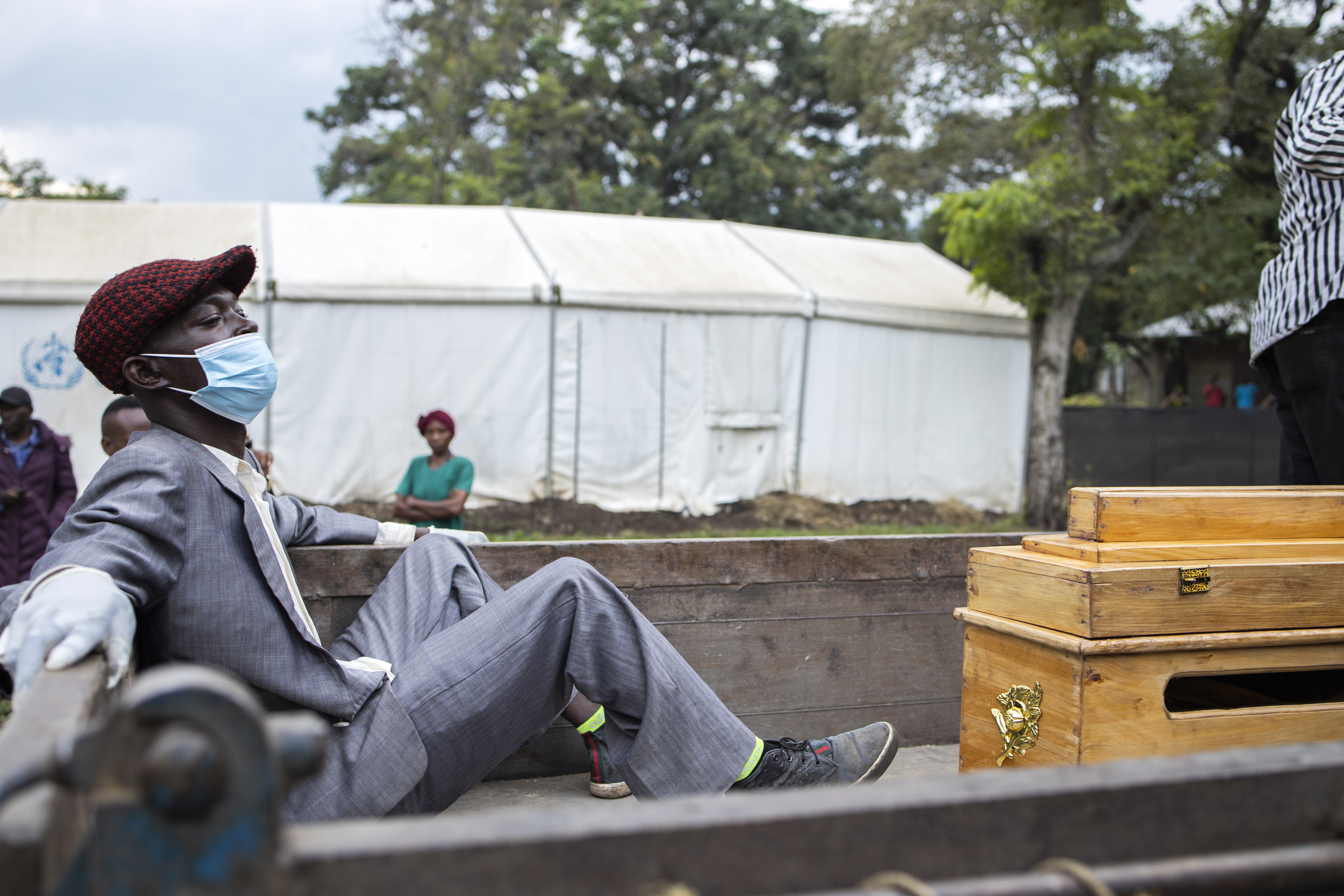 The relative of a victim of the Mpondwe Lhubiriha Secondary School mourns as he sits next to a casket