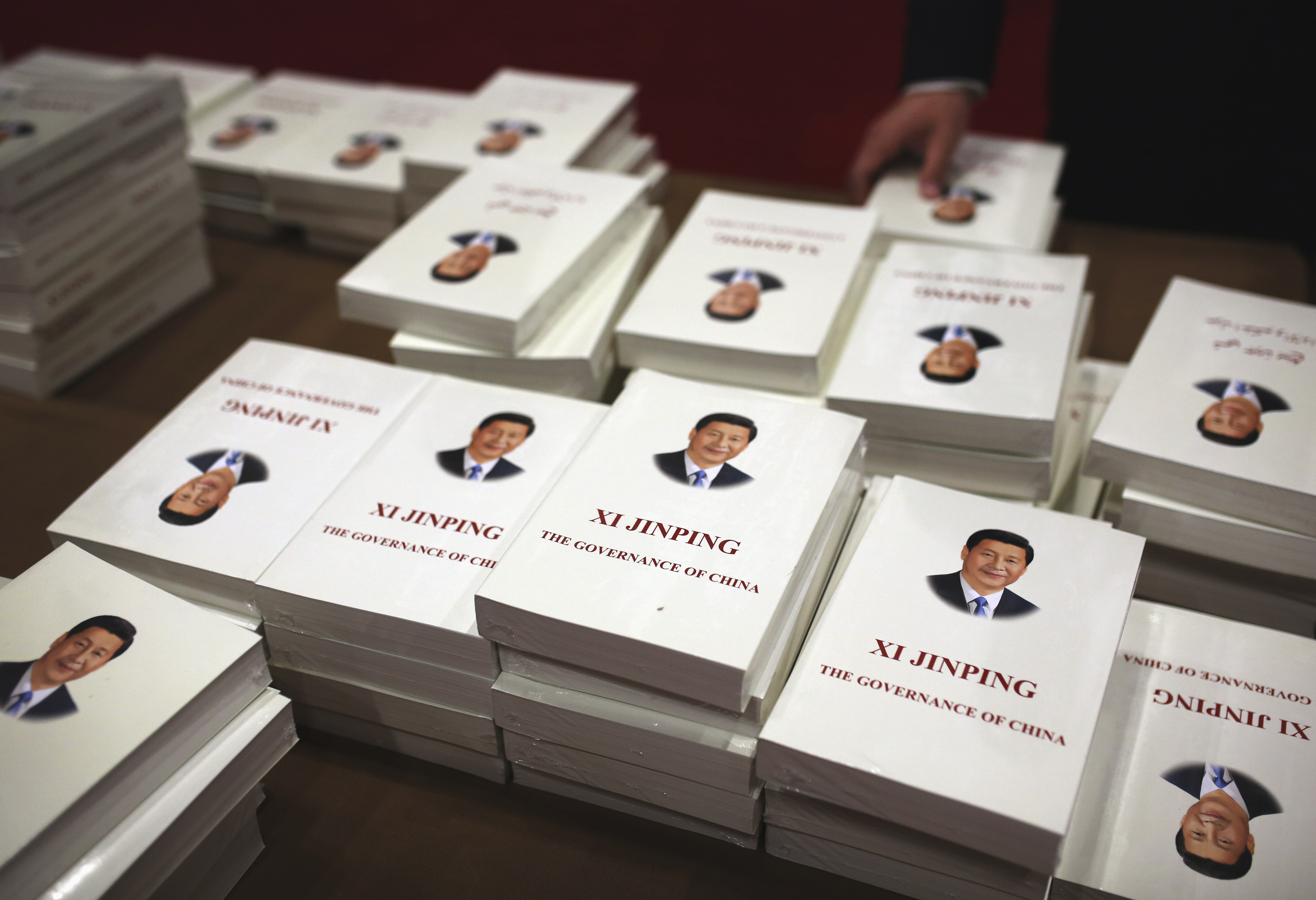 Books by Xi jinping on display. The covers are white and there is a formal portrait of Xi on the cover above the book's title