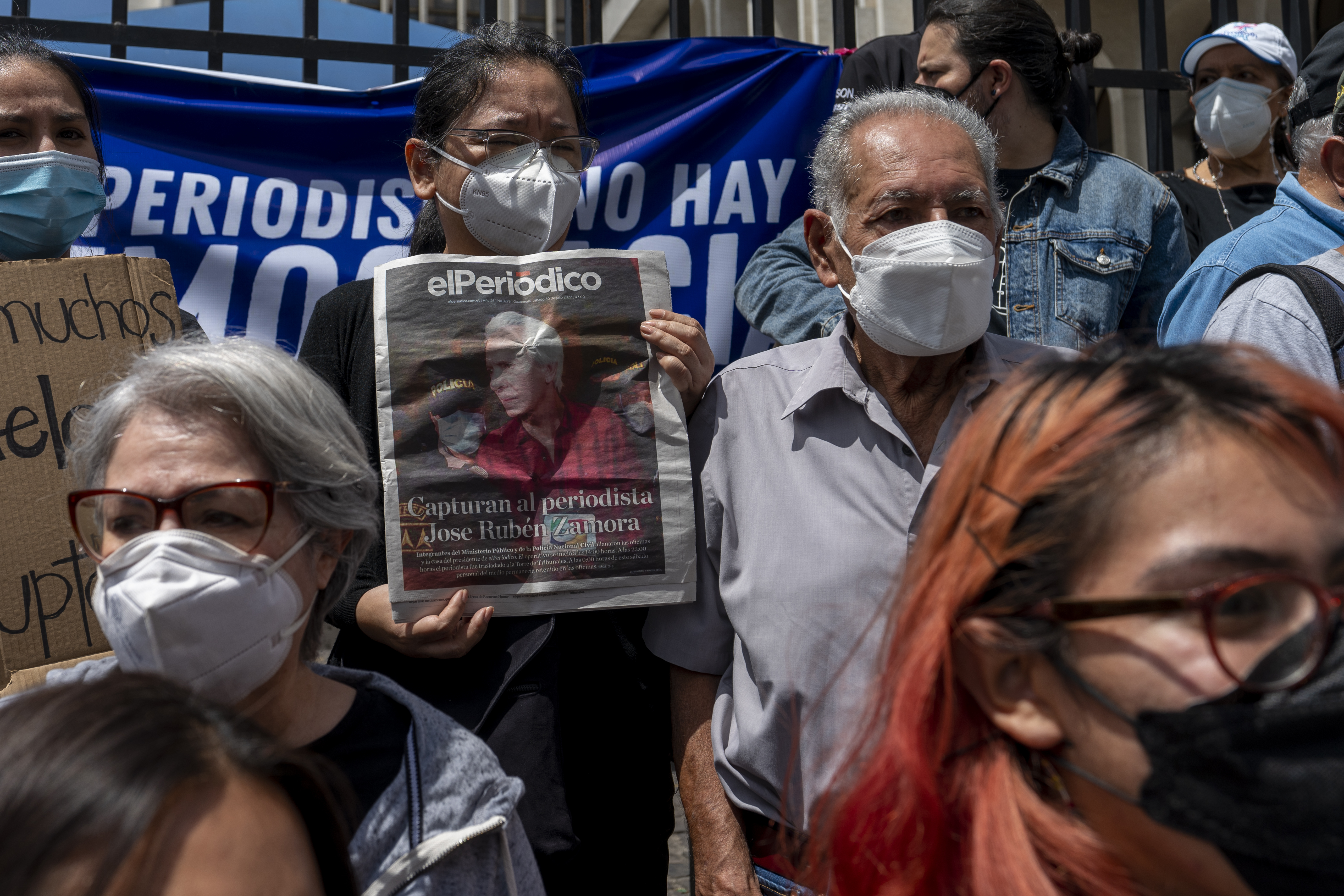 Journalists gather outside a court in protest against the detention of award-winning journalist Jose Ruben Zamora, who was arrested the day before, in Guatemala City, Saturday, July 30. A blue banner can be seen at their protest, and one holds up a copy of the El Periodico newspaper.