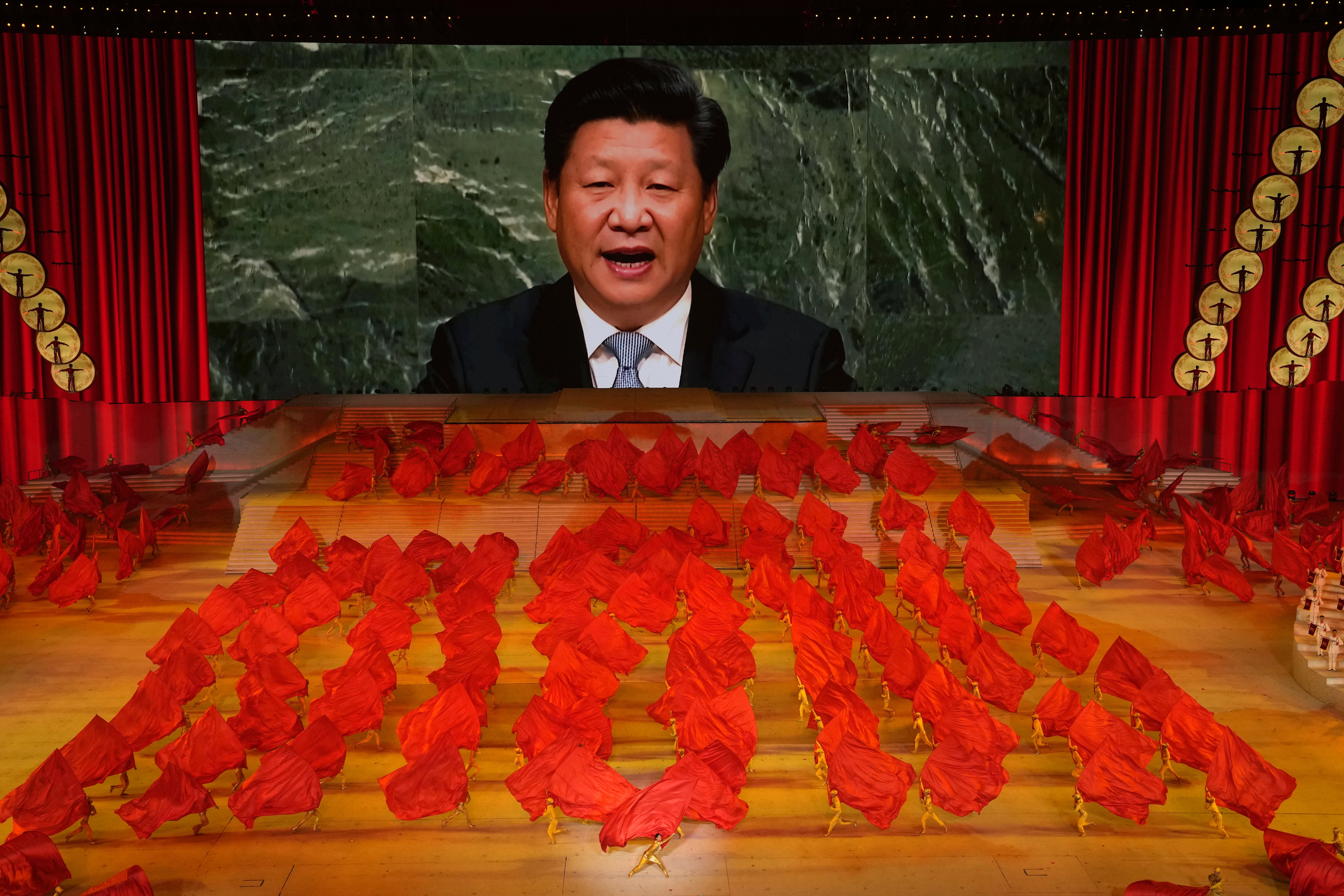 Xi Jinping on a giant screen as performers dance with red flags