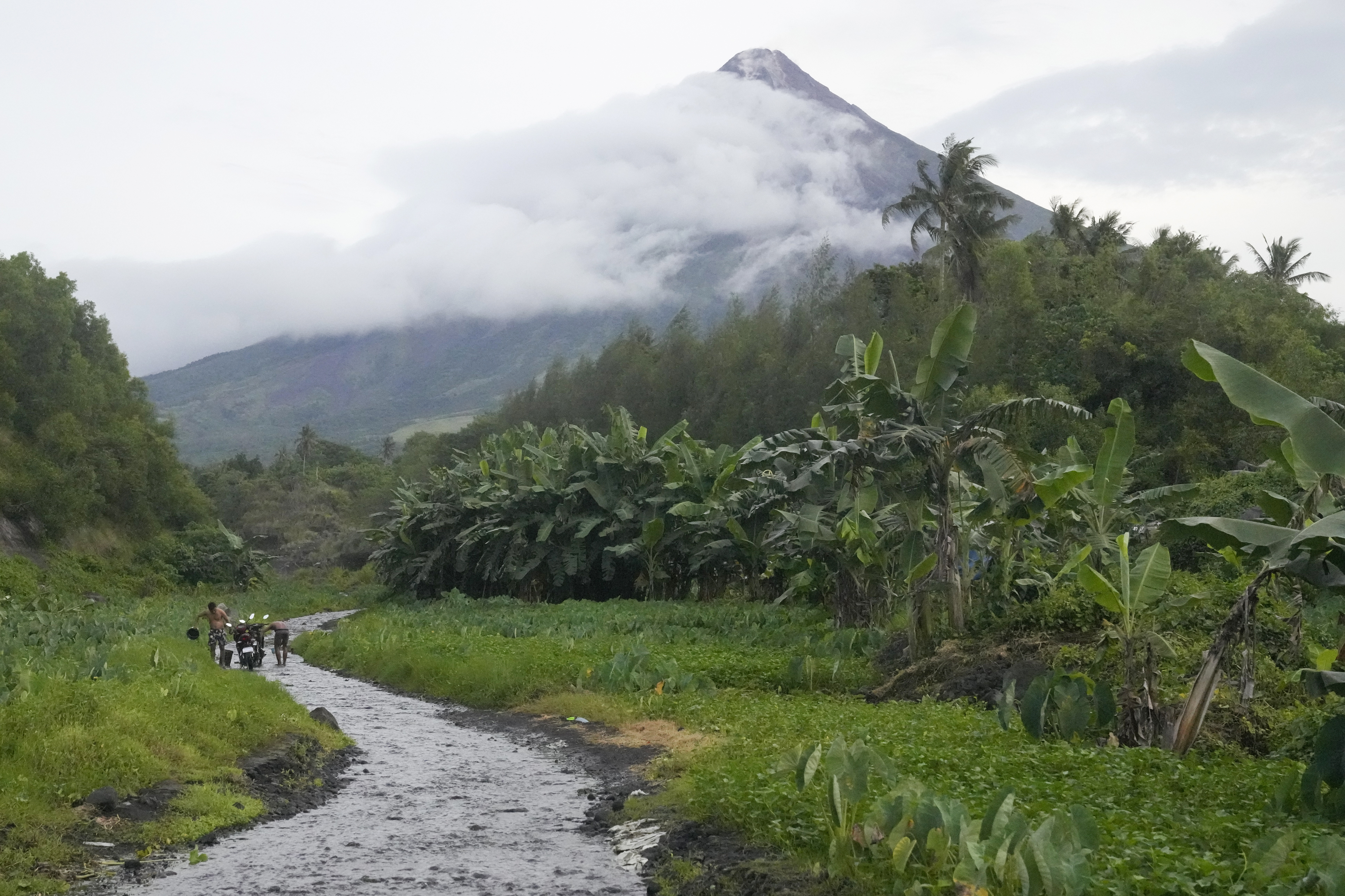 Men wash their motorcycles along a stream near Mayon volcano in Bonga