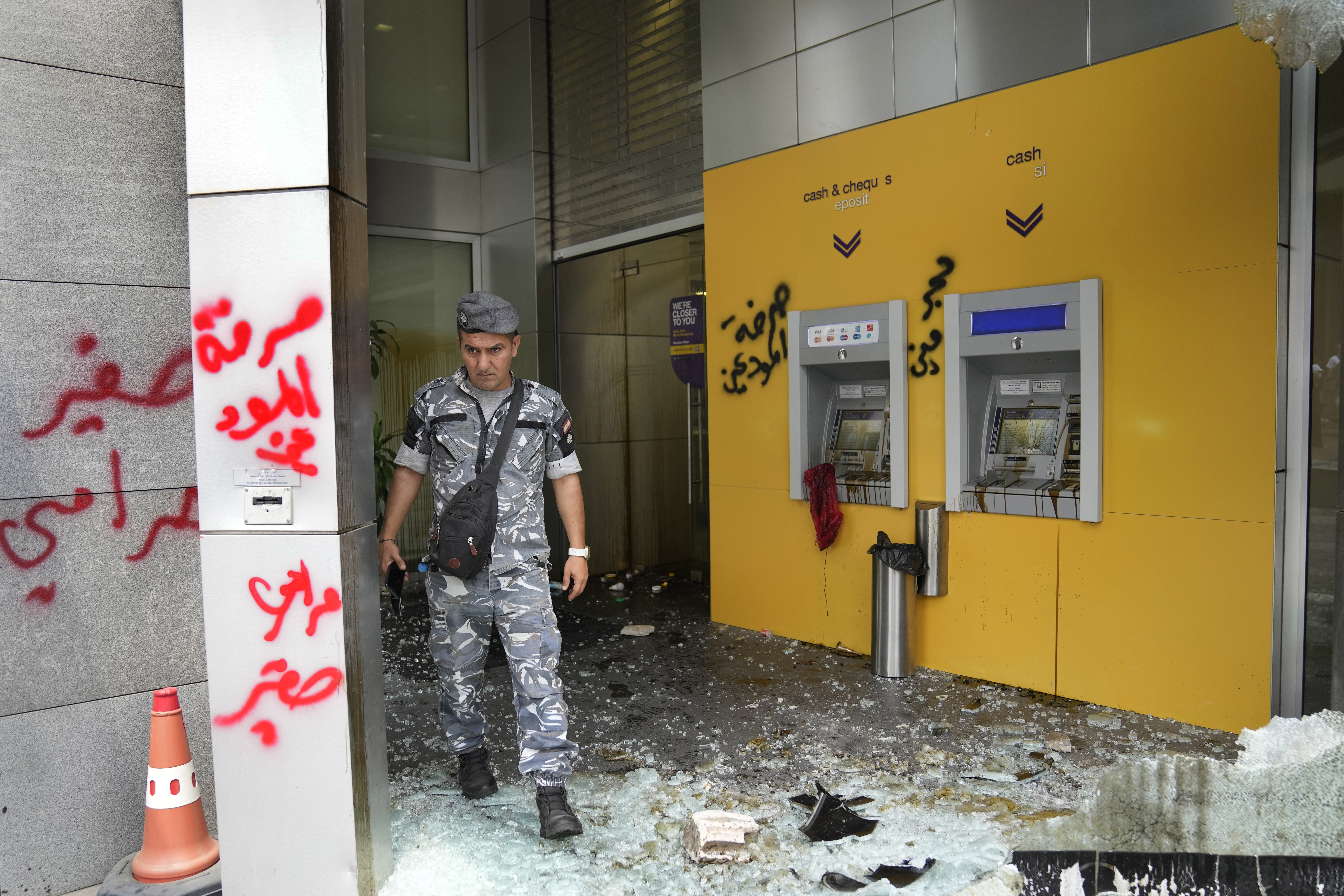 A policeman walks through Byblos bank, which was damaged by angry protesters 