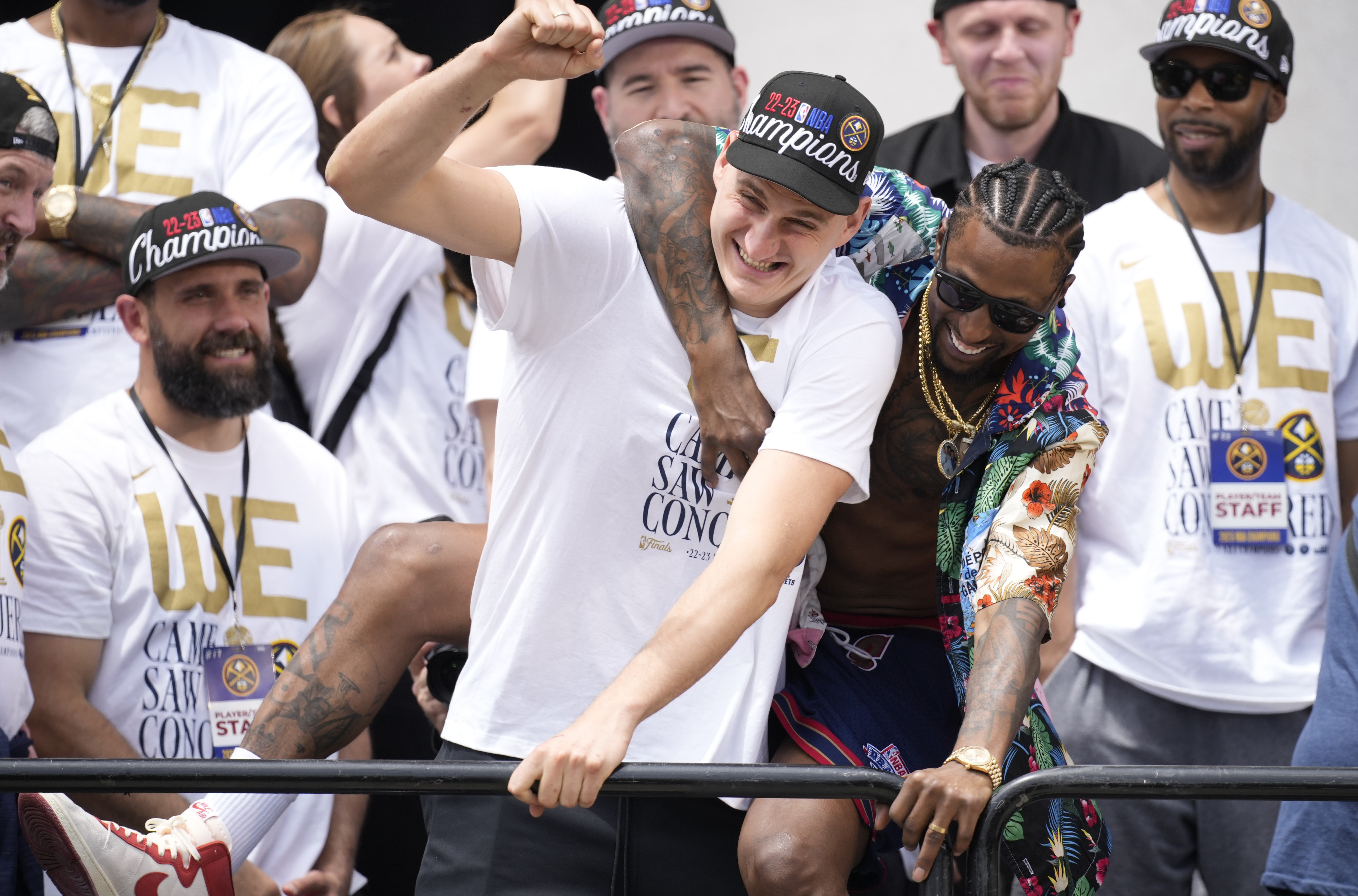 Denver Nuggets center Nikola Jokic, center left, jokes with guard Kentavious Caldwell-Pope, center right, during a rally and parade to mark the team's first NBA basketball championship