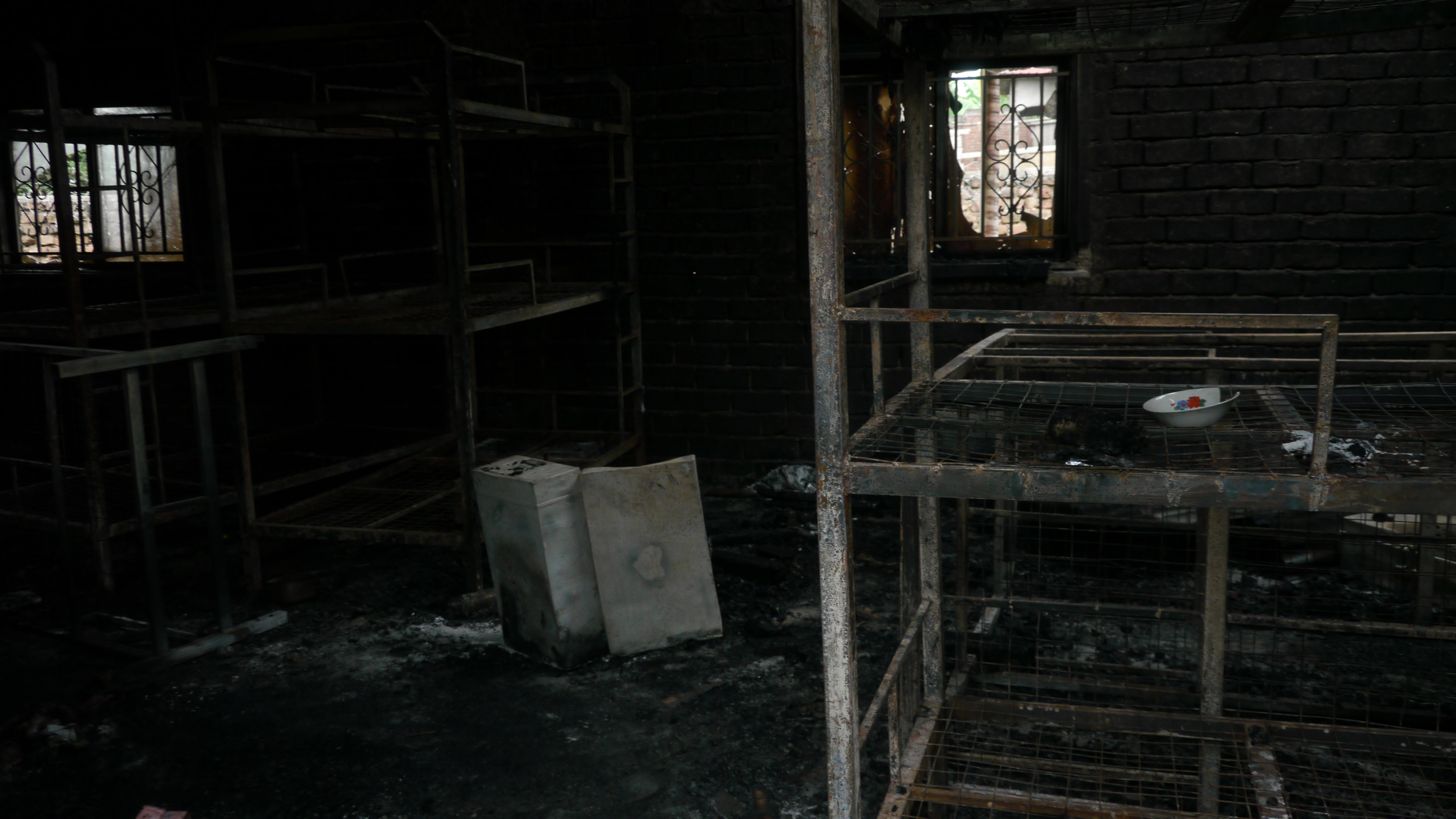 Bunk beds and a few personal items are all that is left in the burnt out boys dorm of Lhubirira Secondary School, Uganda [Sophie Neiman, Al Jazeera]