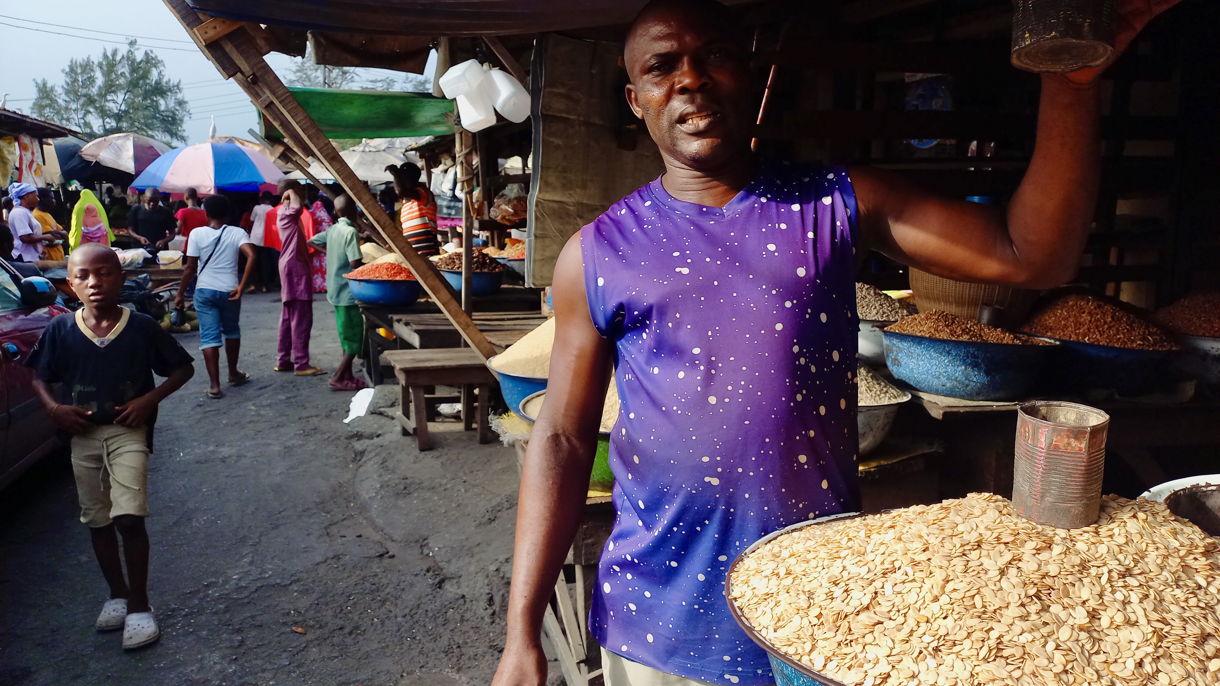 A salesman in Lagos shows the tin he uses to measure seeds.