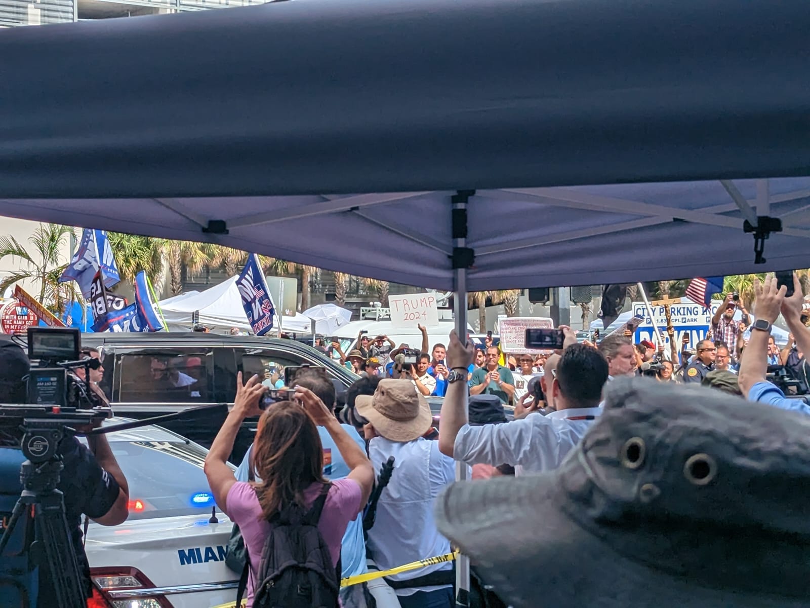 People take photos of car carrying former President Donald Trump as he leaves the courthouse
