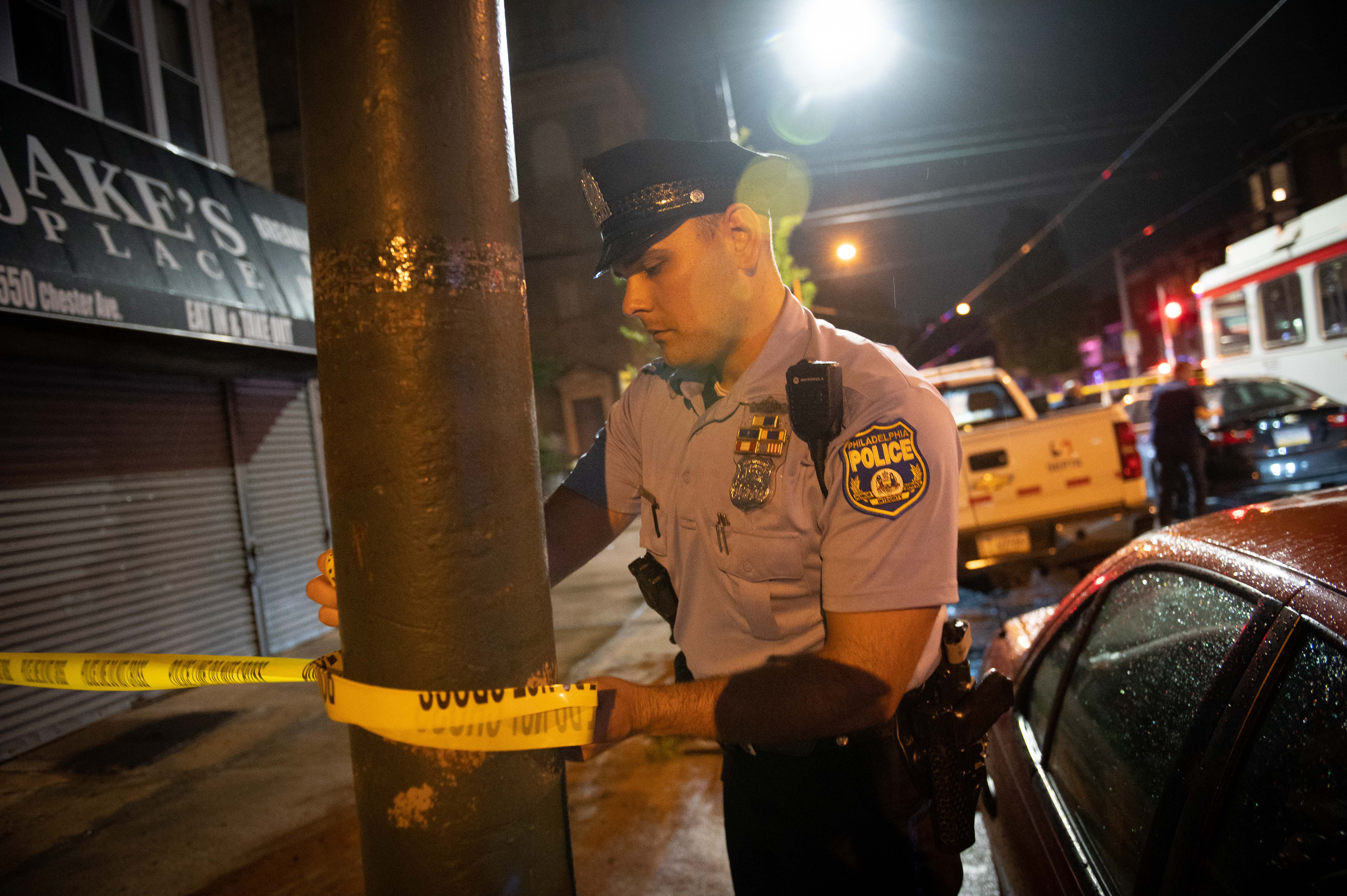 Police officials work at the scene of a mass shooting in the Kingsessing section of South Philadelphia