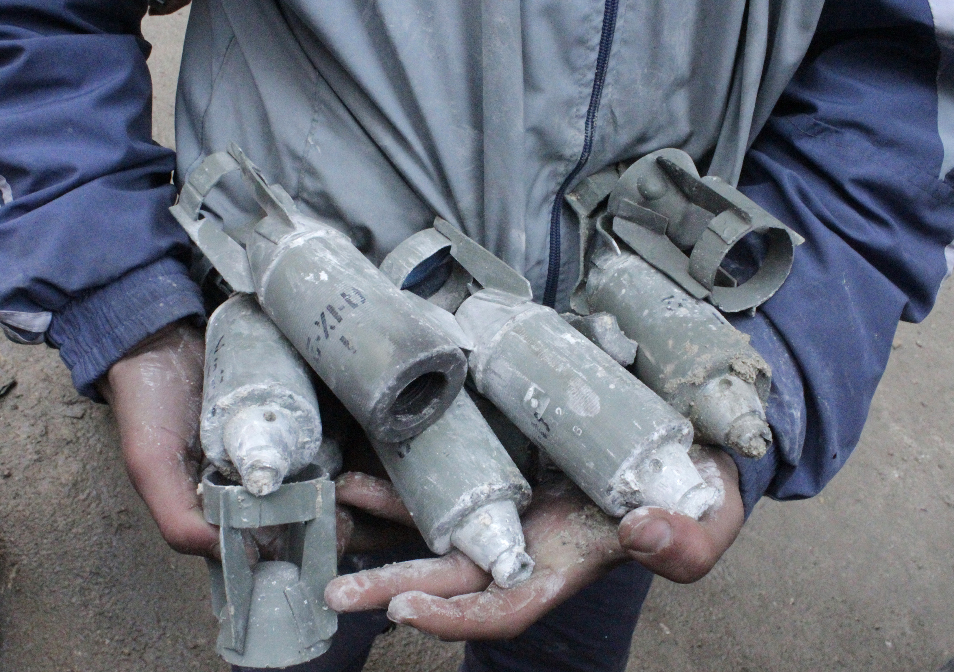 A boy holds unexploded cluster bombs