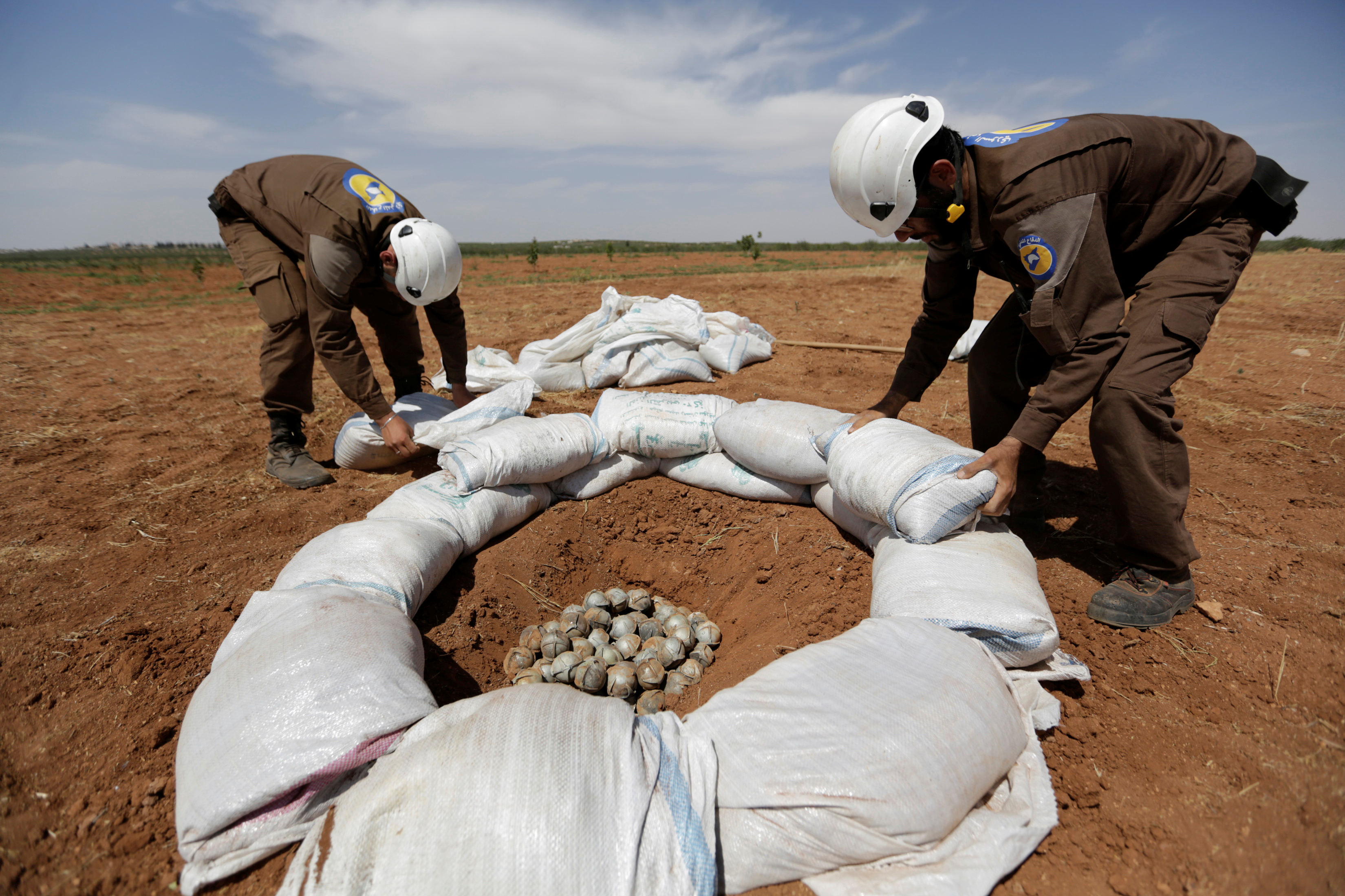 Civil defence members gather cluster bombs to safely detonate them
