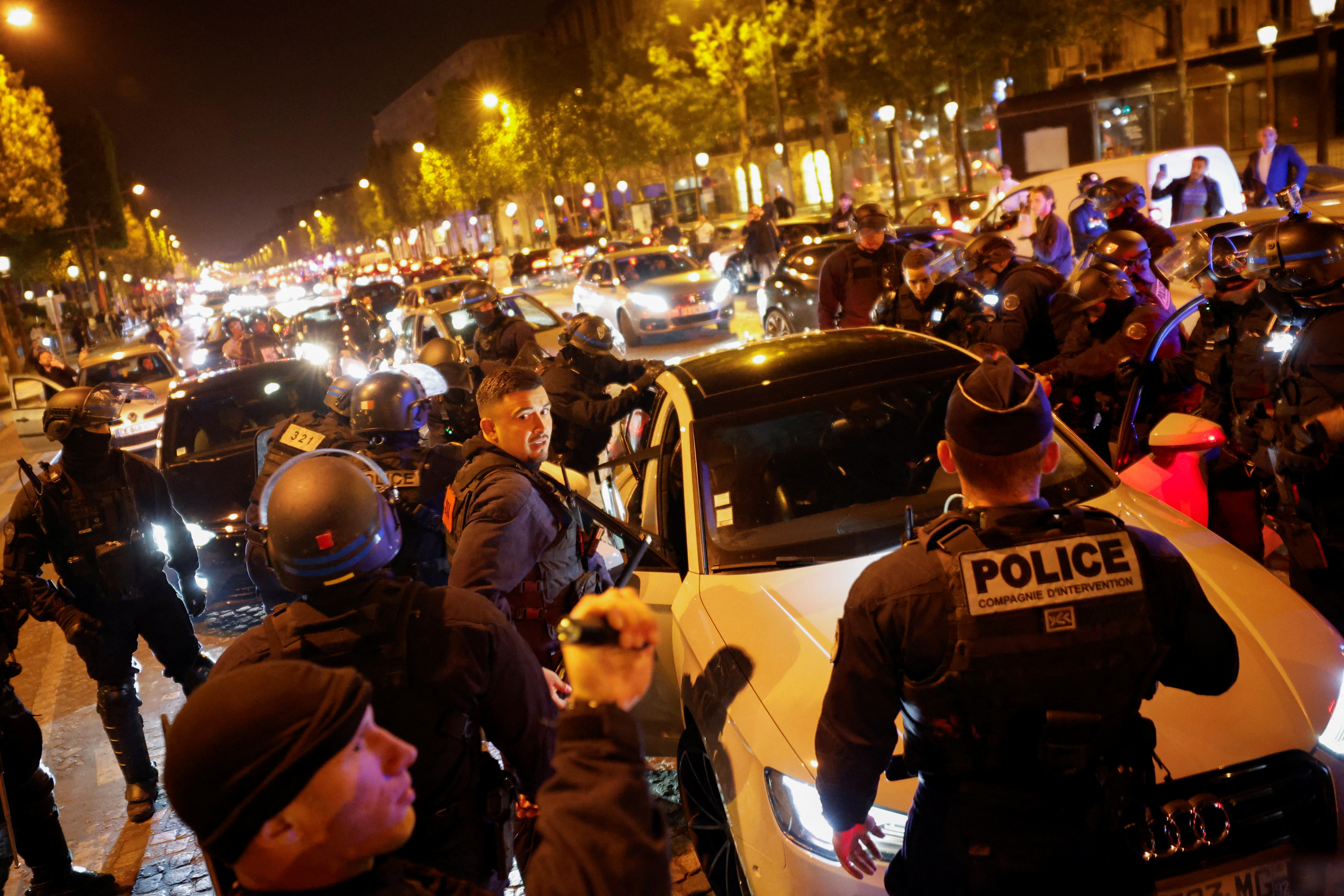 Police hold young people against a vehicle during the fifth night of protests following the death of Nahel, a 17-year-old teenager killed by a French police officer