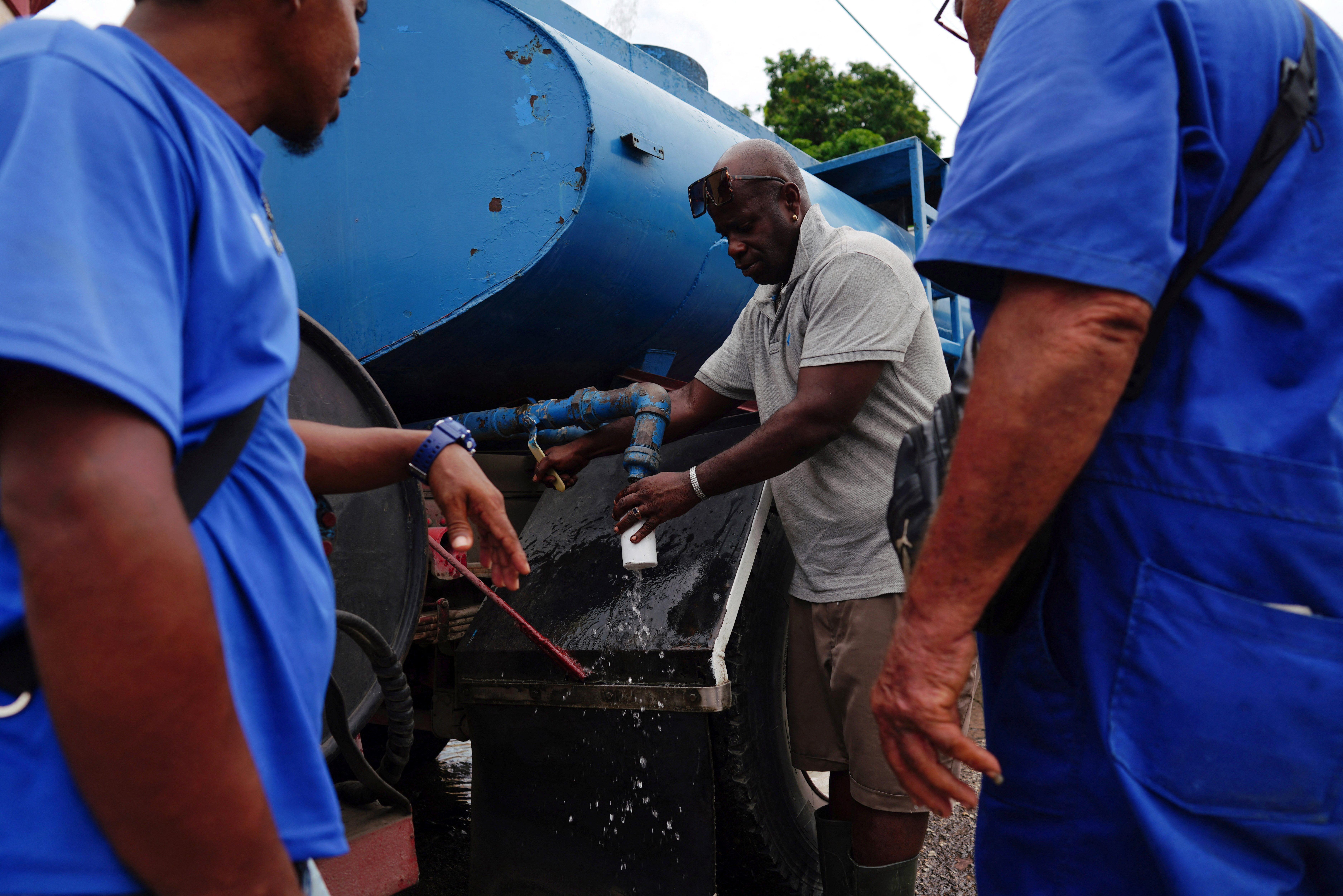 Drivers prepare to drink water as they wait for their turn to fill up water trucks in Havana, Cuba,