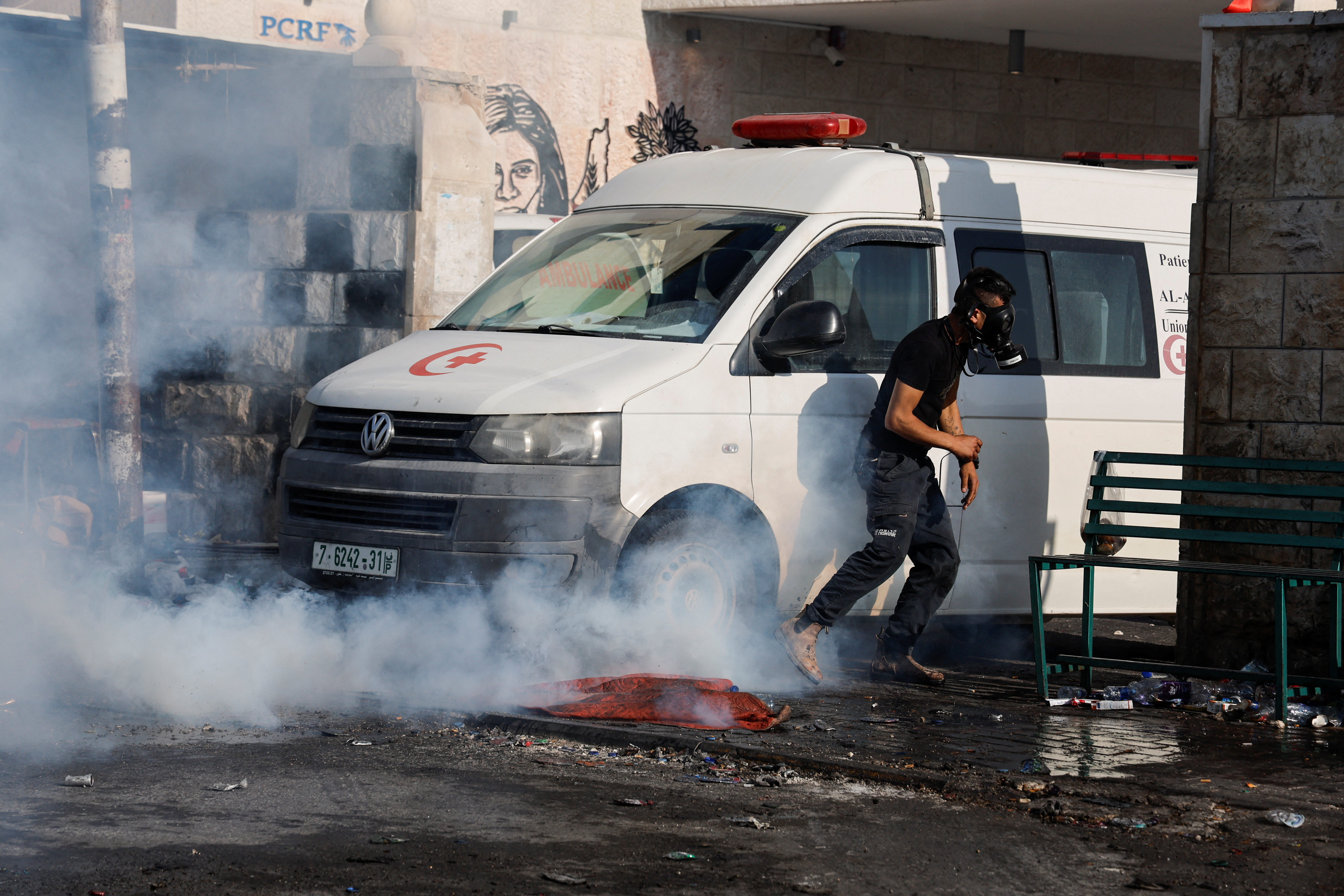 A person wears a gas mask during clashes between Palestinians and Israeli forces amid an Israeli military operation, in Jenin, in the Israeli-occupied West Bank