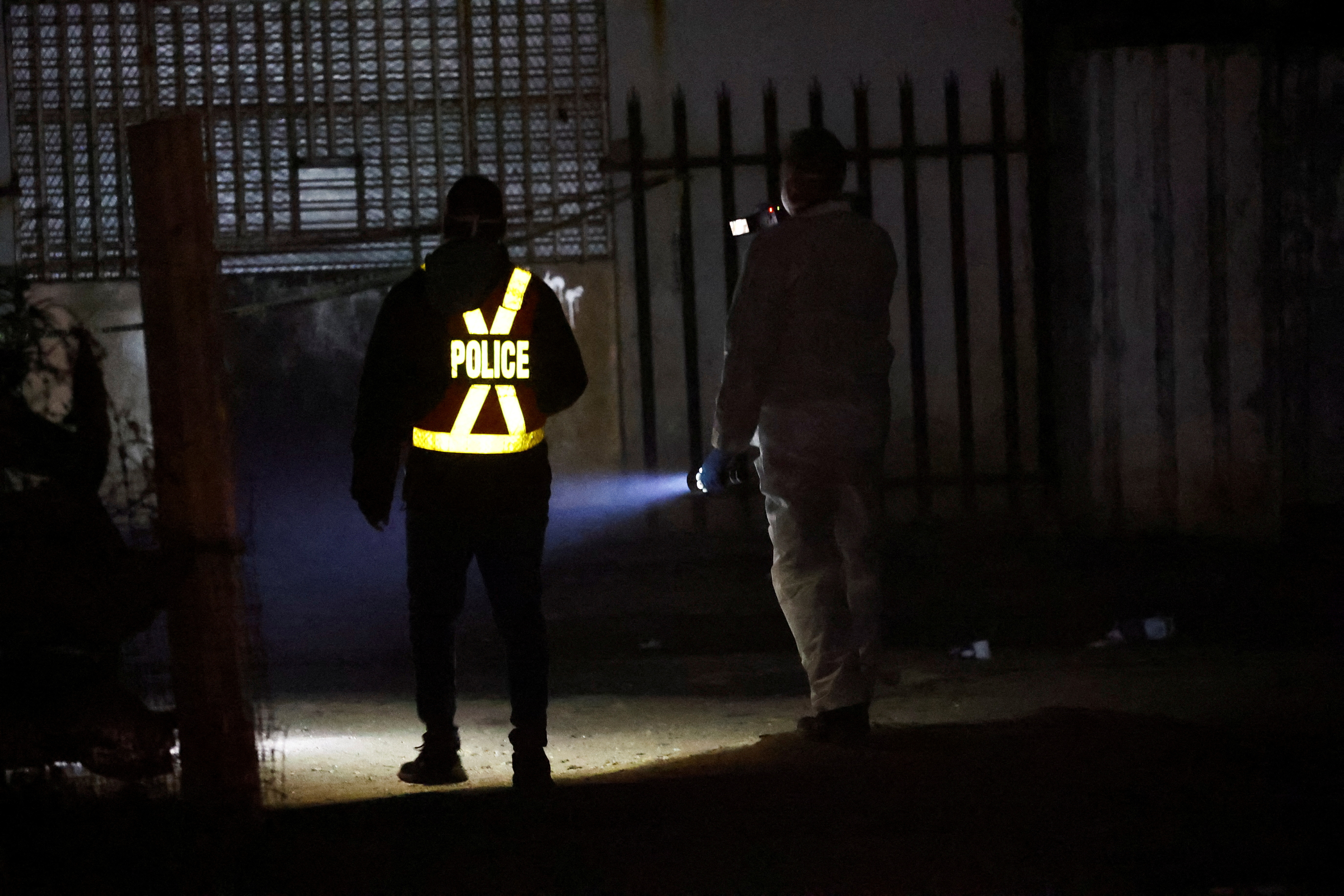 A police officer and a member of the forensic team inspect the scene of a suspected gas leak linked to illegal mining, in the Angelo shack settlement, near Boksburg, east of Johannesburg, South Africa July 6, 2023