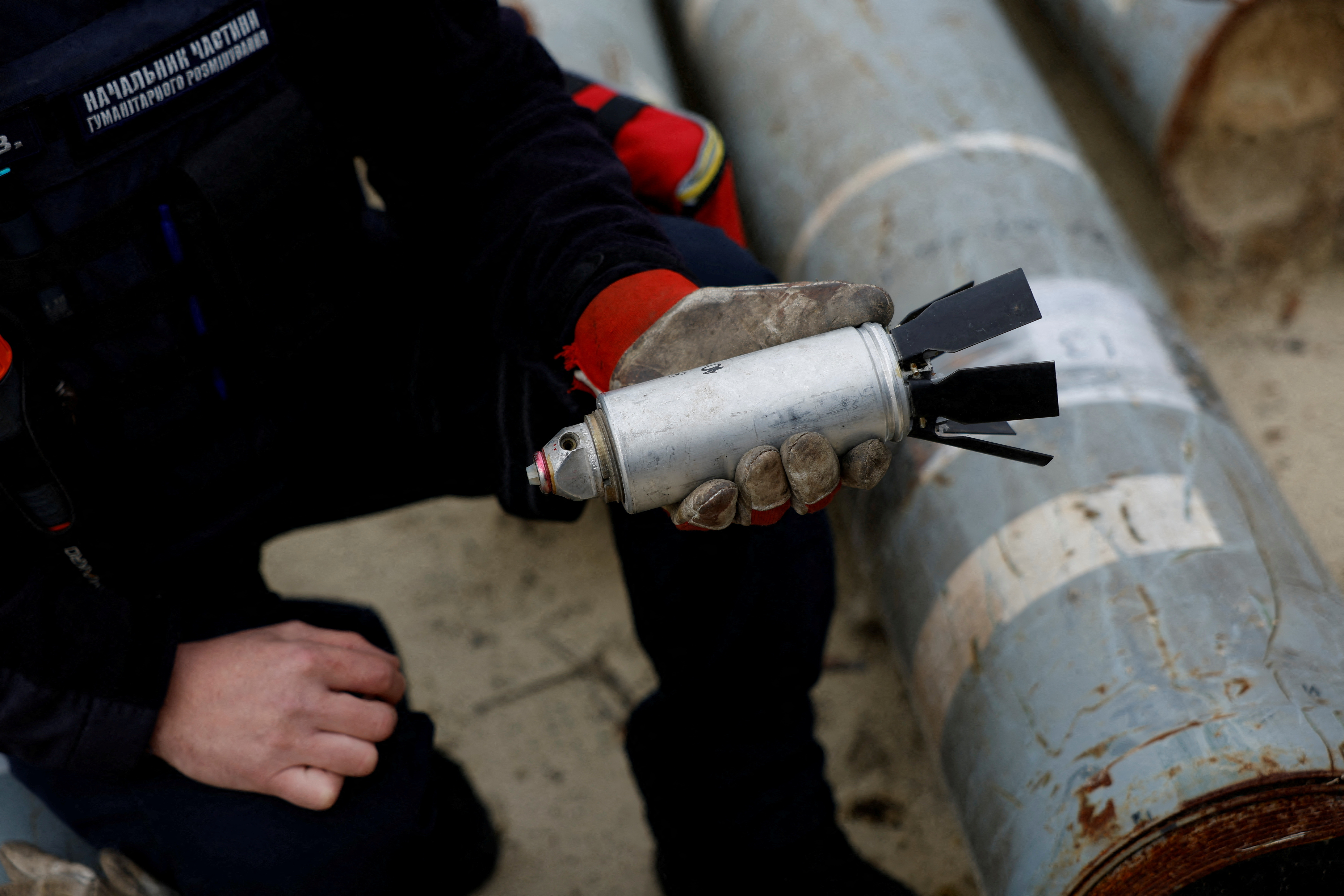 A Ukrainian serviceman holds a defused cluster bomb from an MSLR missile allegedly used by the Russian army