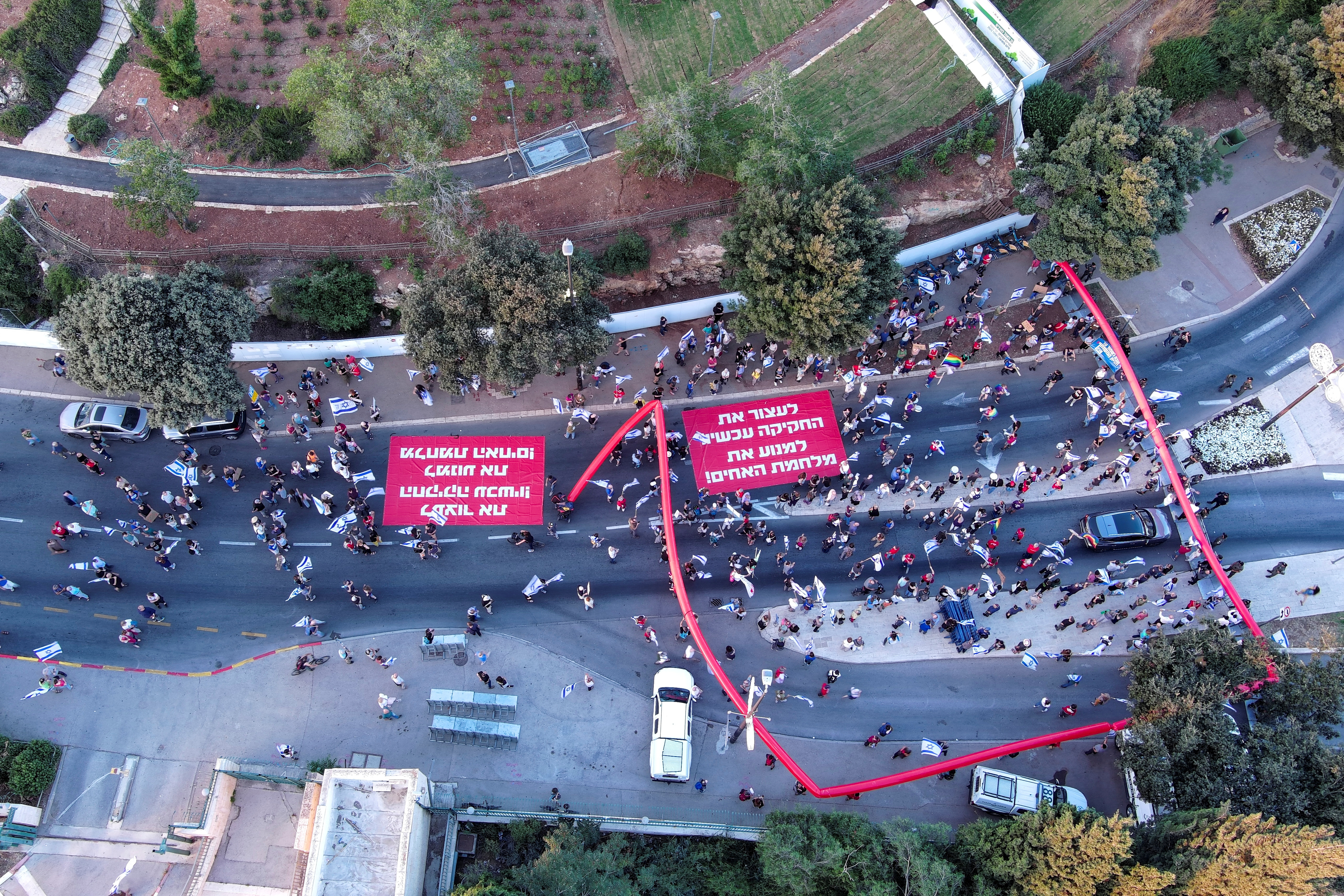 An aerial view shows people holding a sign in Hebrew which reads "stop the legislation now to prevent a civil war" as they take part in a demonstration against Israeli Prime Minister Benjamin Netanyahu and his nationalist coalition government's judicial overhaul