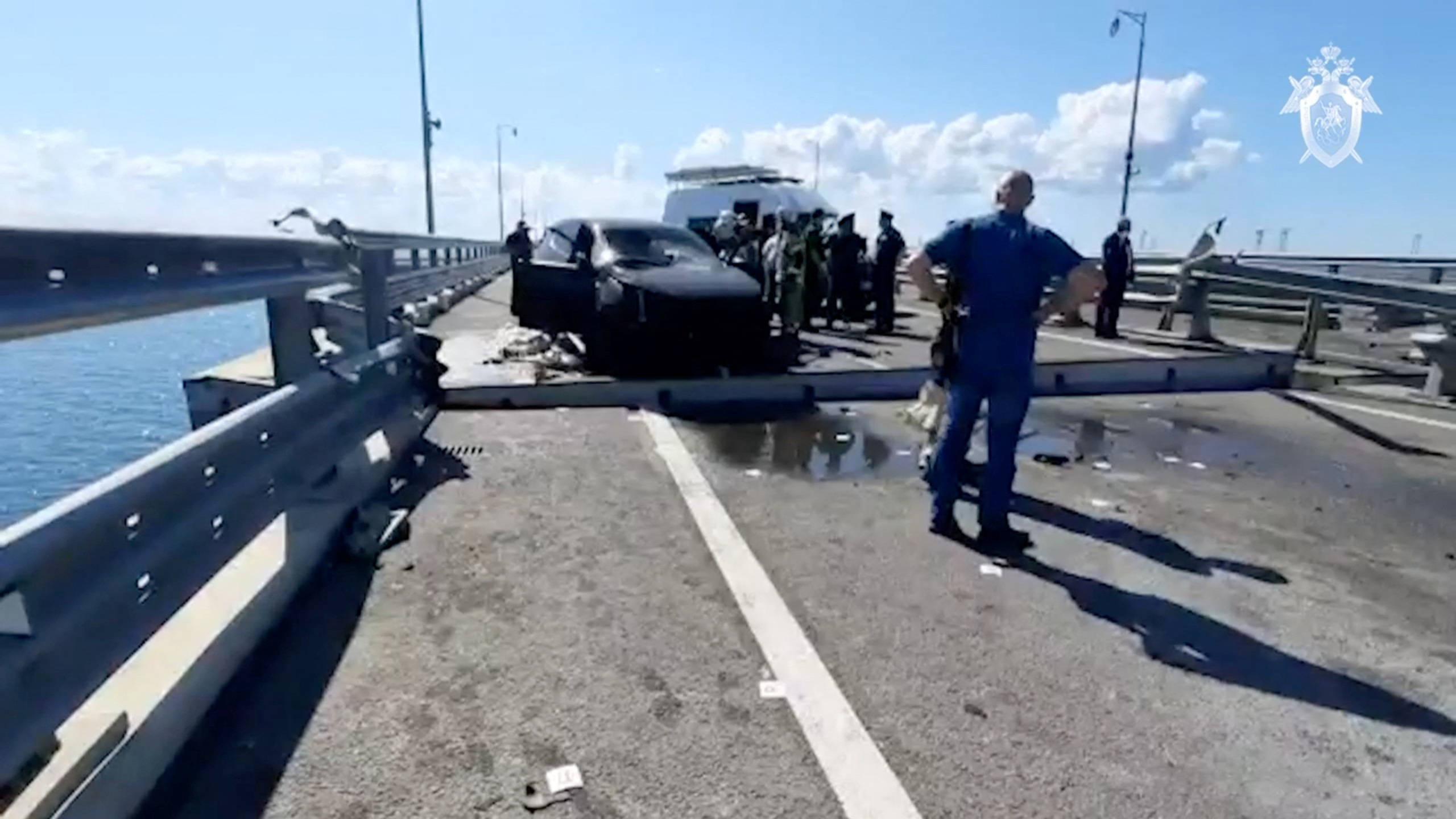 Russian investigators and emergency services' members gather near a destroyed car at the accident scene on the damaged section of a road following an alleged attack on the Crimea Bridge, that connects the Russian mainland with the Crimean peninsula across the Kerch Strait, in this still image taken from video released July 17, 2023. Investigative Committee of Russia/Handout via REUTERS ATTENTION EDITORS - THIS IMAGE WAS PROVIDED BY A THIRD PARTY. NO RESALES. NO ARCHIVES. MANDATORY CREDIT. WATERMARK FROM SOURCE. 